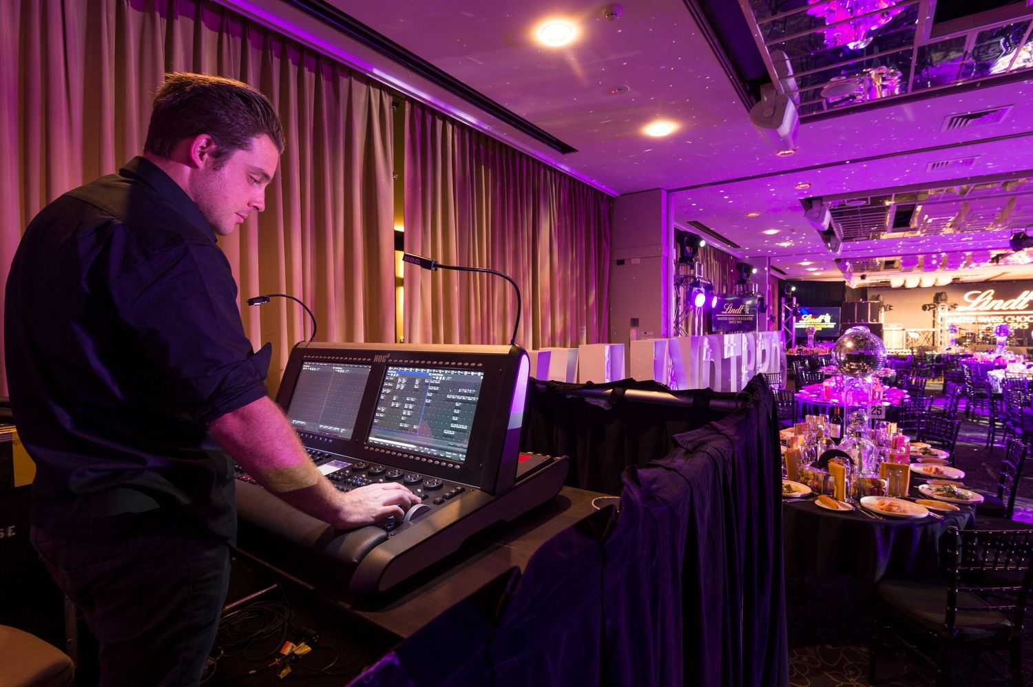 A dimly lit nightclub interior with purple lighting and electronic equipment visible across multiple angles.