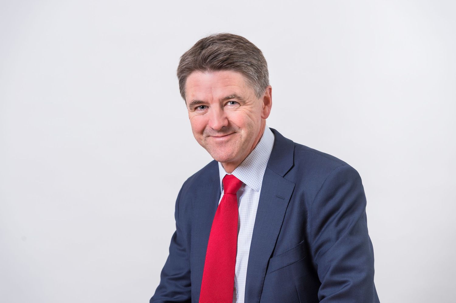 Corporate headshots featuring person wearing navy suit with red tie.