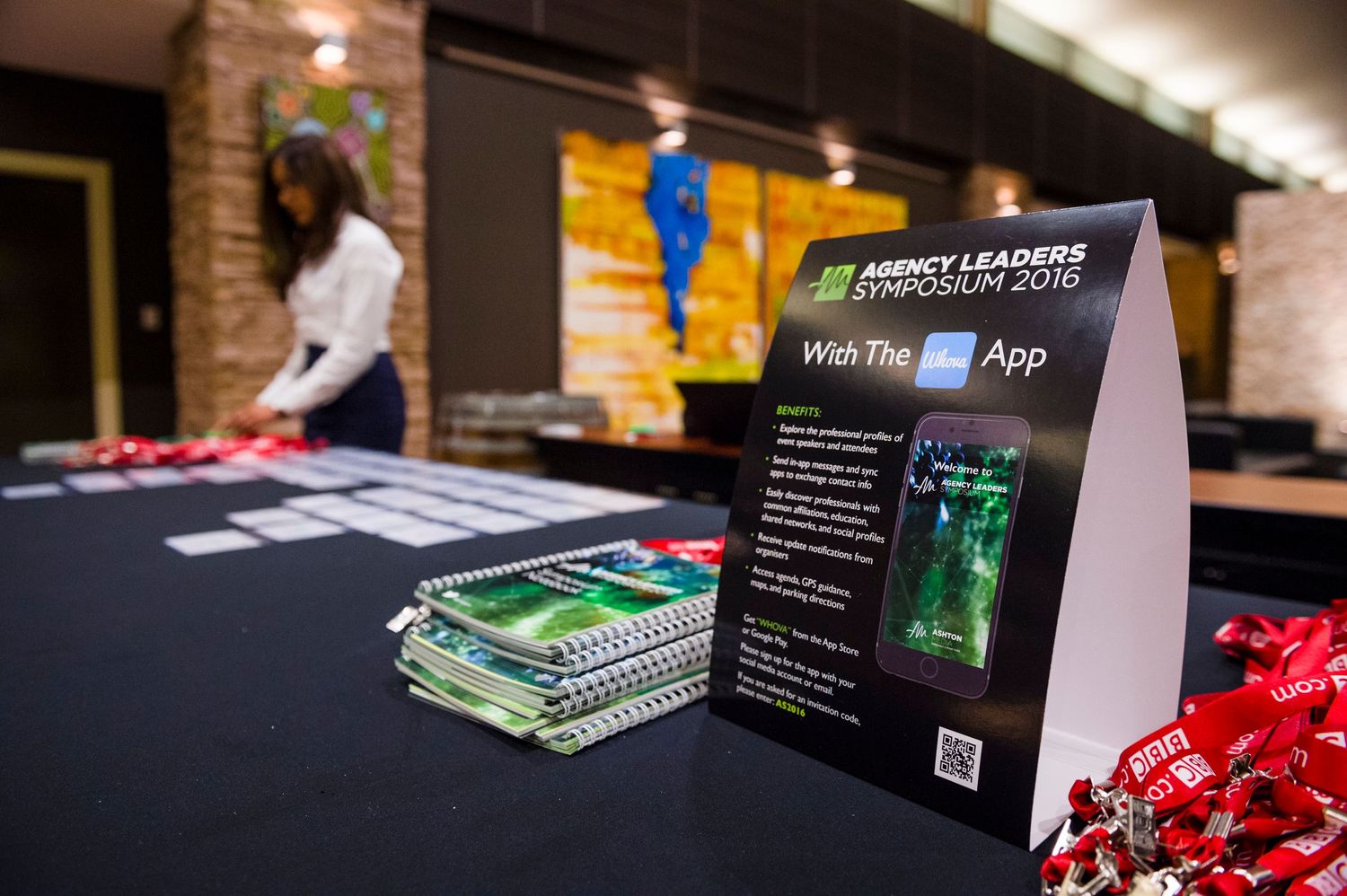 Marketing materials and branded literature displayed on dark table at professional event.