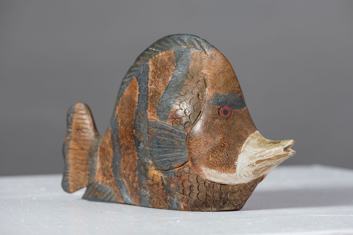 Ancient Greek ceramic fish vessel with brown and black painted details displayed from multiple angles on a gray surface.