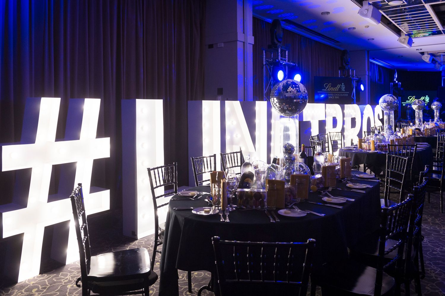 Modern event venue with elegant table settings and dramatic lighting creating a sophisticated atmosphere.