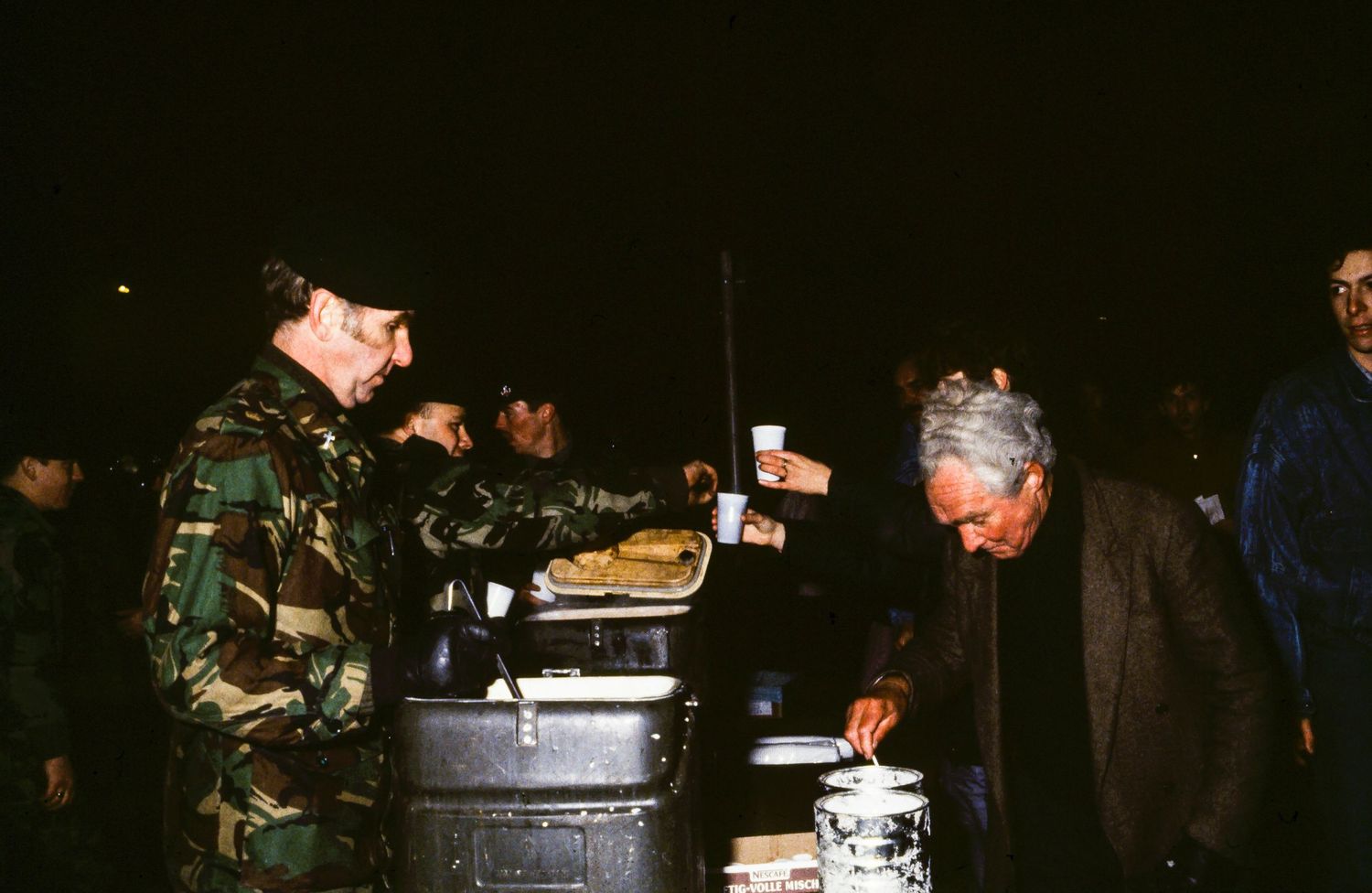 Dark nighttime scene showing activity near the Berlin Wall.