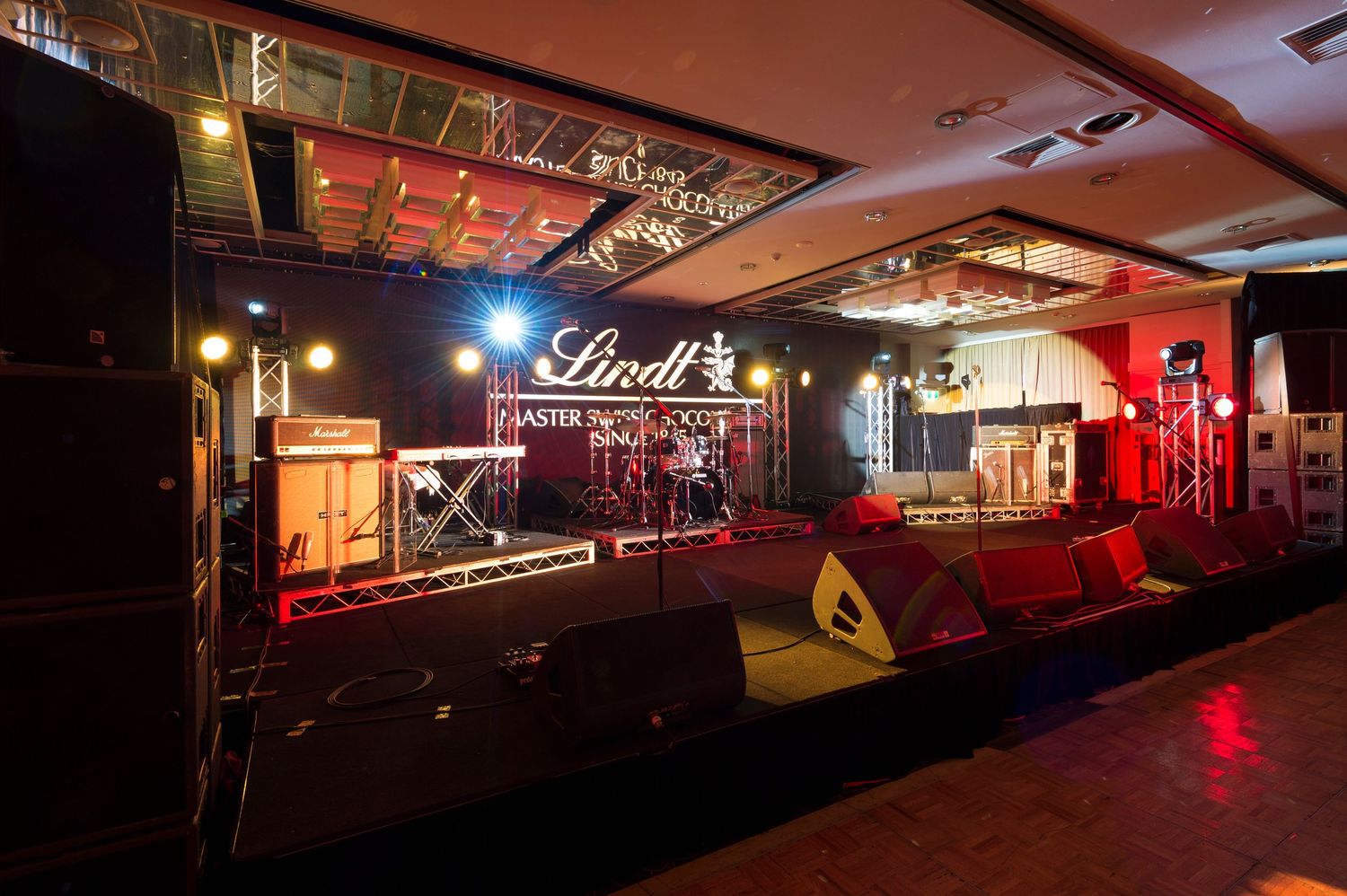 A dimly lit nightclub interior with red lighting and a Lindt logo sign glowing on the wall.