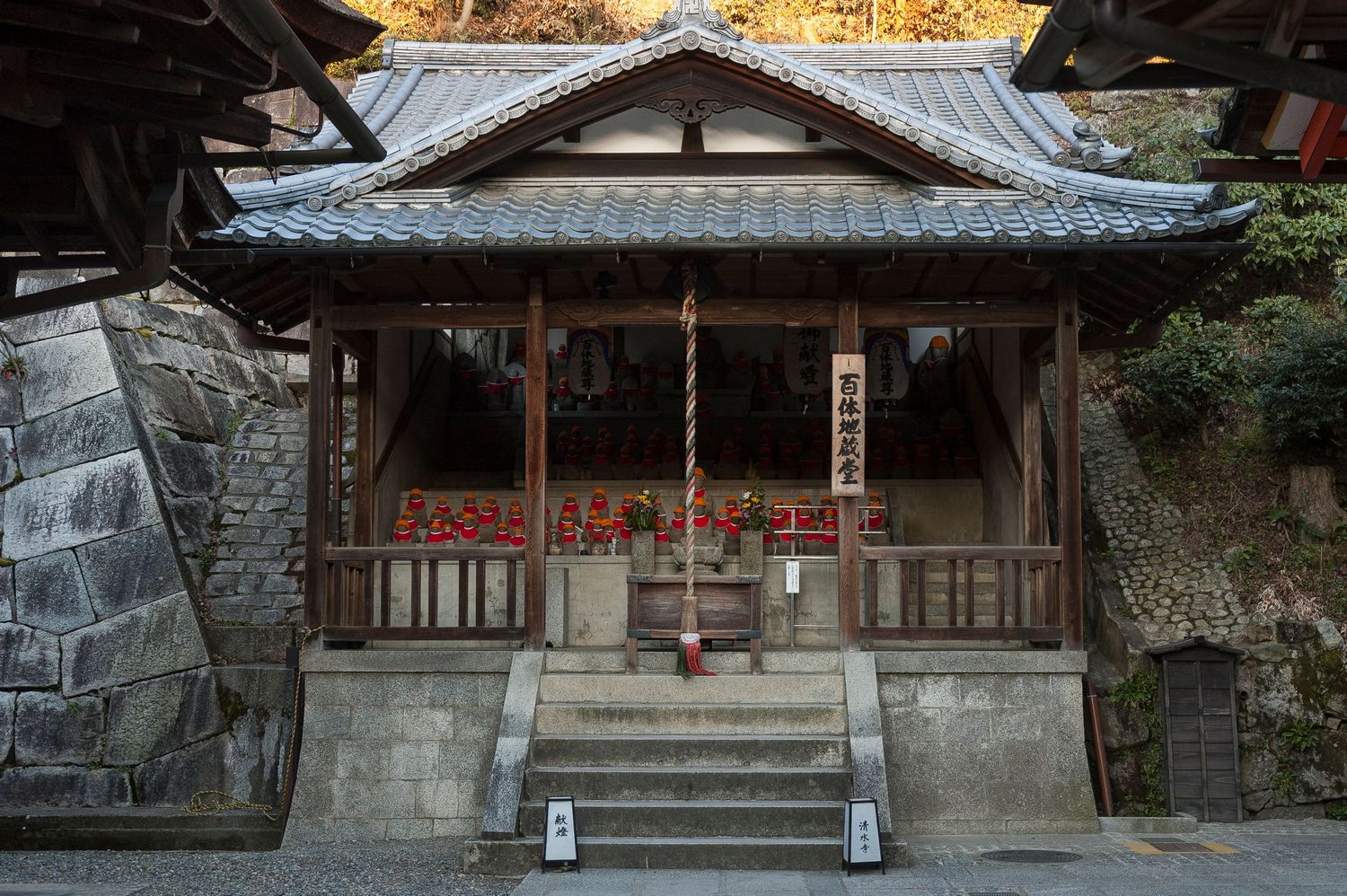 Stone steps leading to a traditional Japanese shrine entrance with wooden roof and stone lanterns.