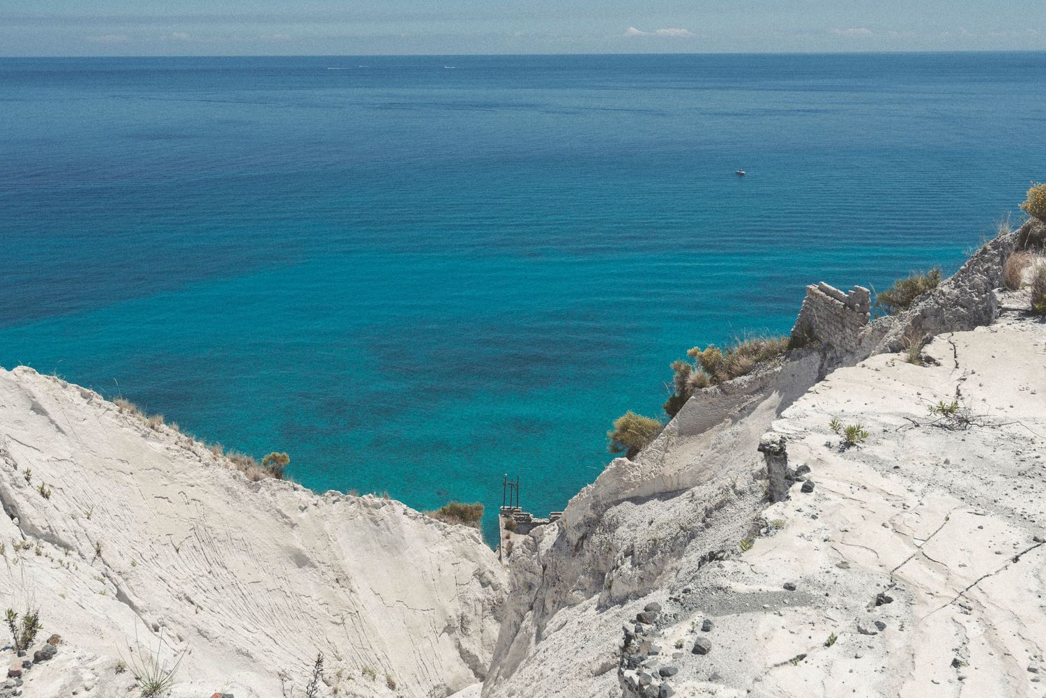 Aerial view of rugged coastal cliffs overlooking turquoise Caribbean waters on a sunny day.