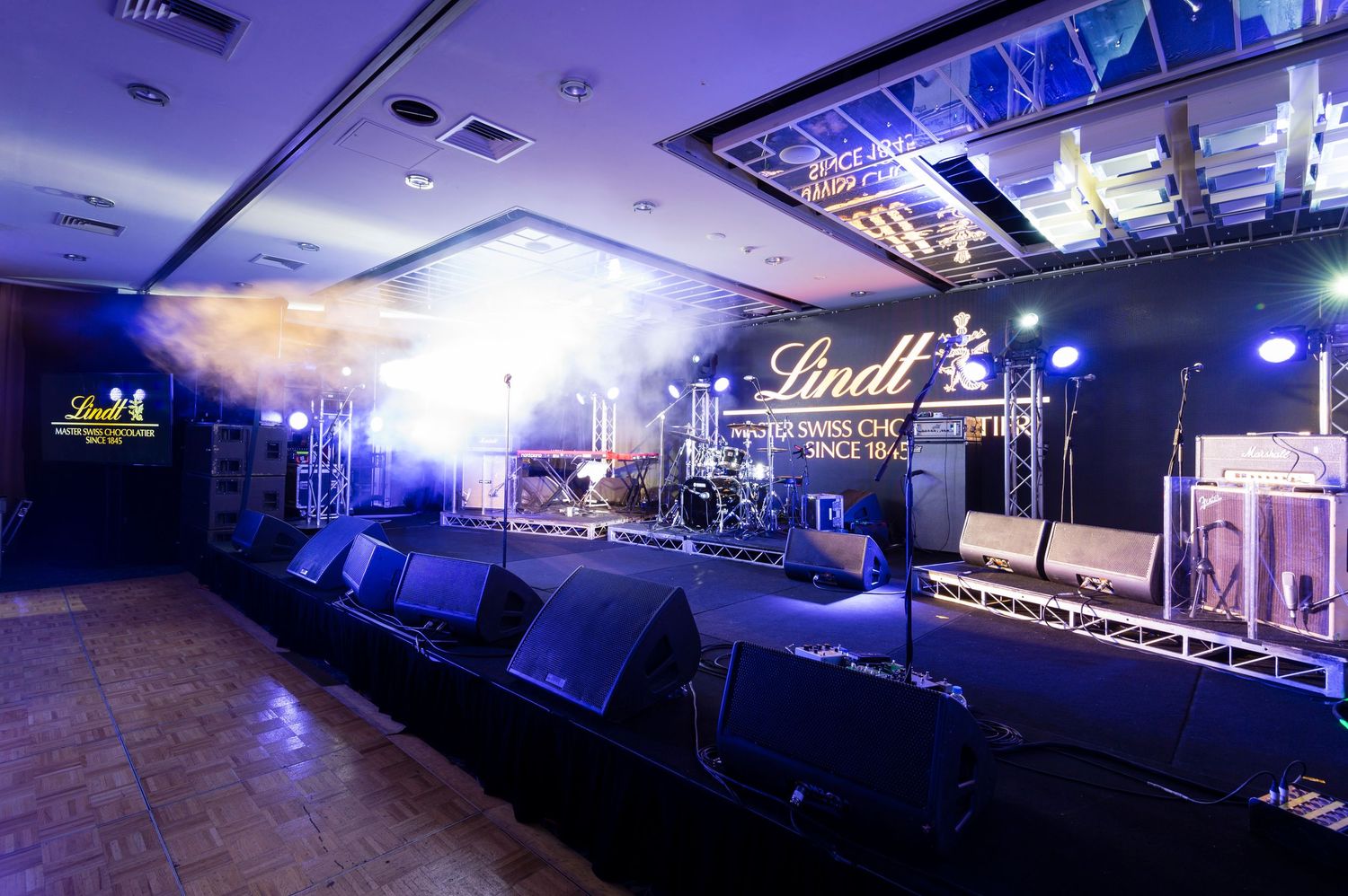 Interior view of a dimly lit nightclub with blue lighting and stage setup visible across multiple angles.