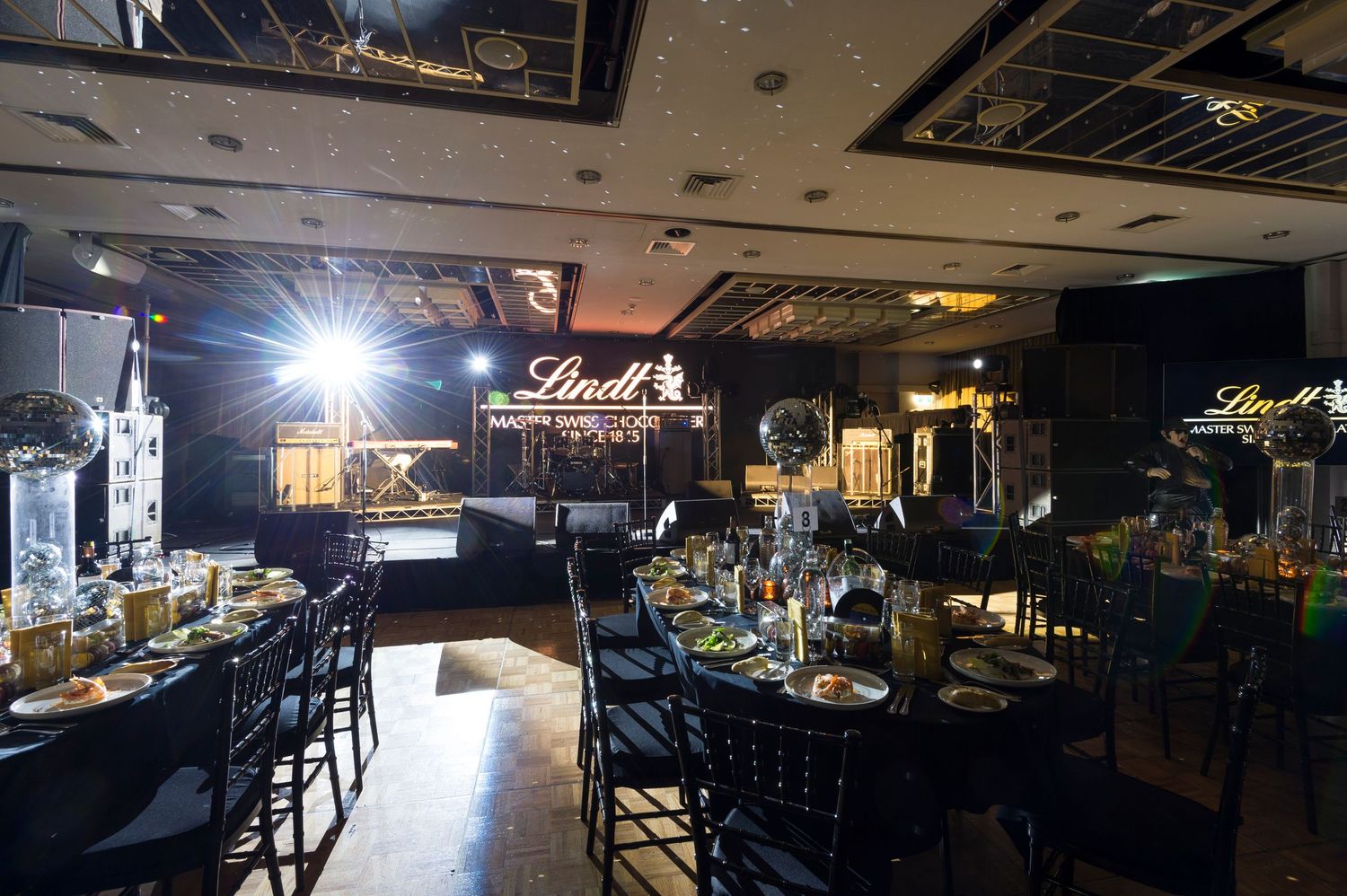 Dark interior of a bar or nightclub with ambient lighting showing multiple seating areas and architectural details.