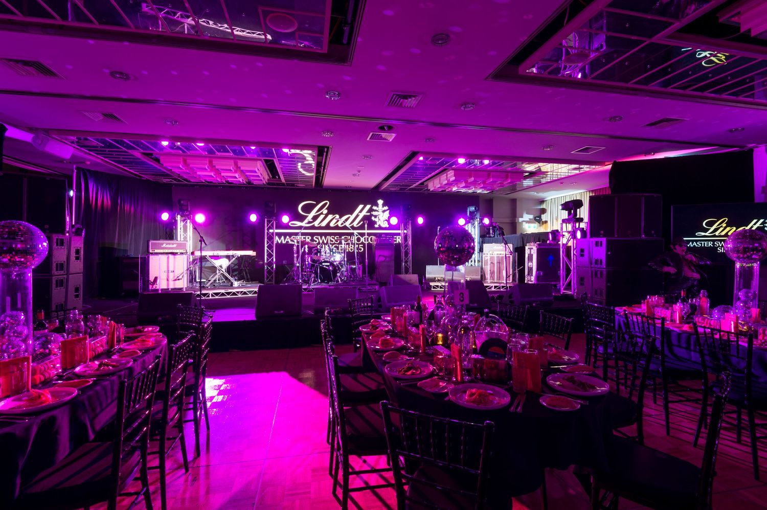 A nightclub interior illuminated in vibrant purple lighting with multiple seating areas and dance spaces.