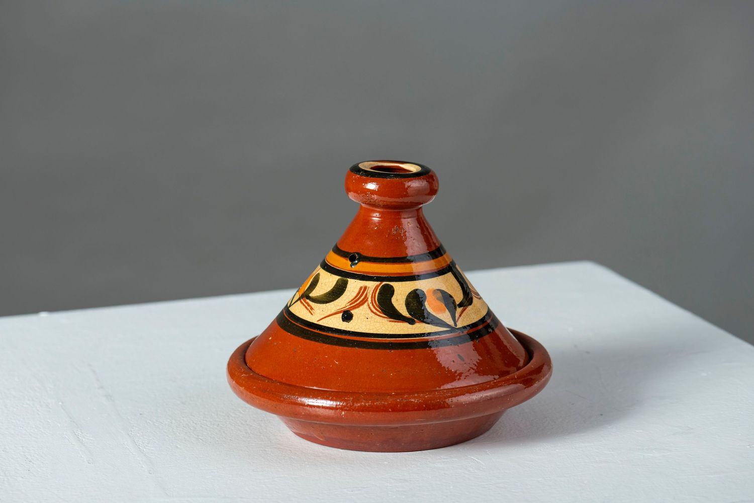 Handcrafted terracotta tagine pot with decorative orange glaze and traditional Moroccan patterns shown from multiple angles.