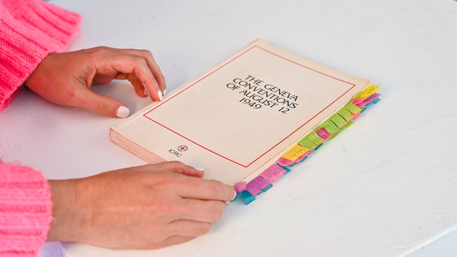 A person's hands flipping through a book with colorful sticky note tabs marking different pages.