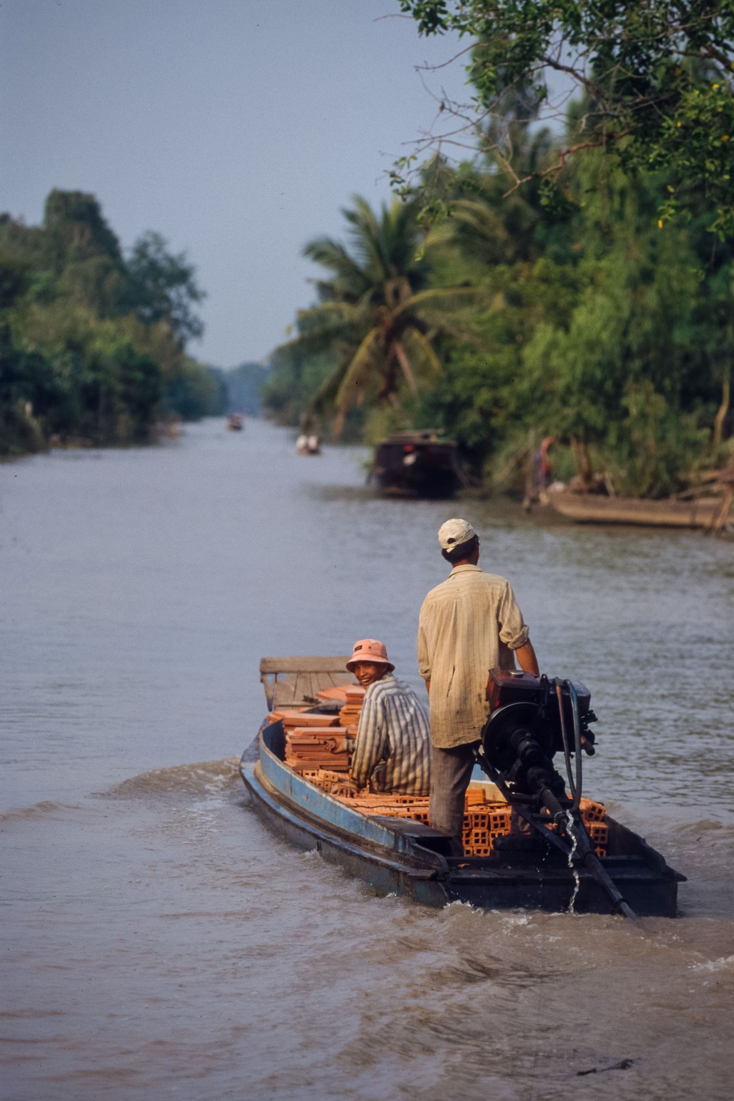 Small wooden boats navigate through palm-lined waterways in the Mekong Delta.
