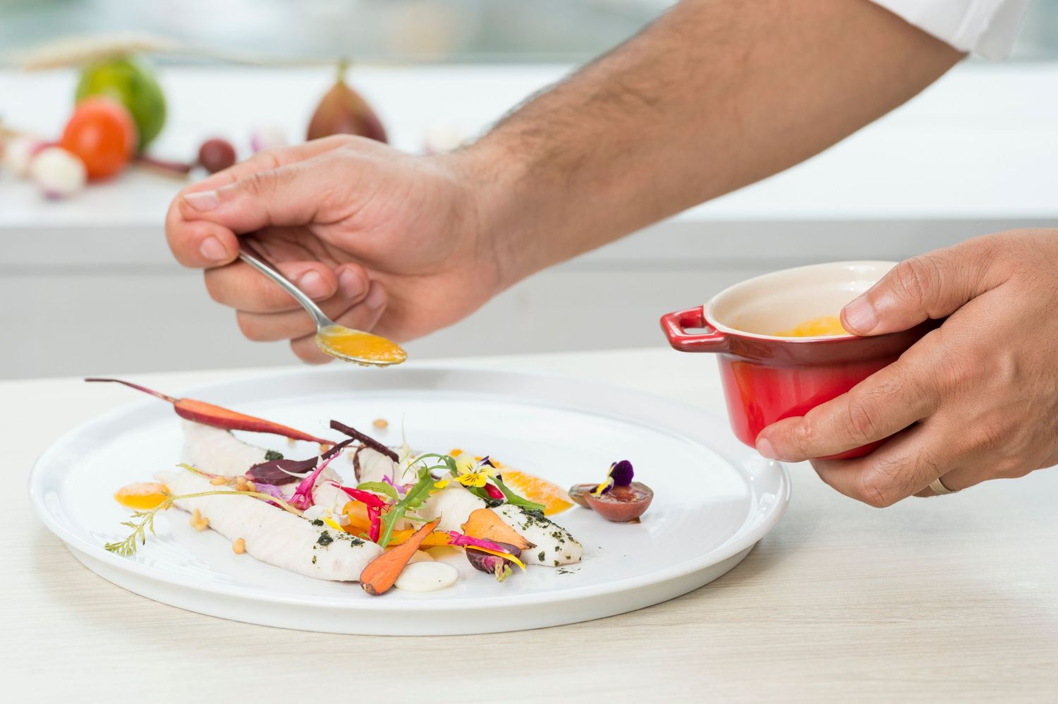 Professional hands carefully plating and garnishing dishes with colorful ingredients.