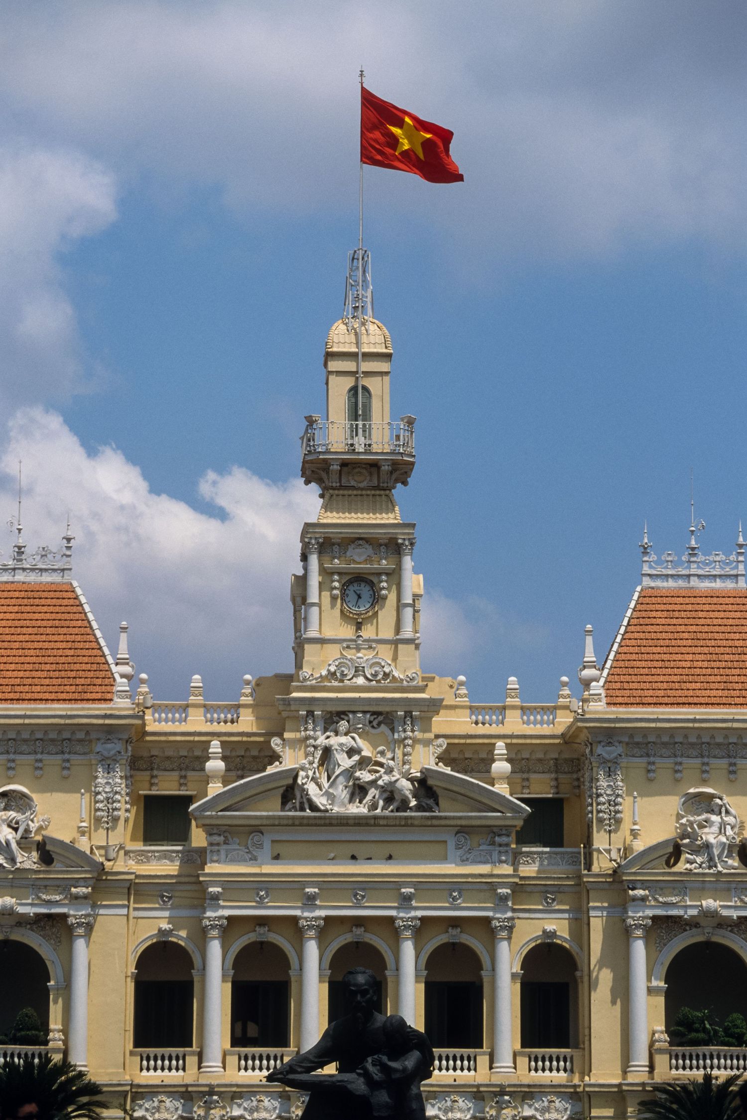 Colonial French architecture of Ho Chi Minh City Hall with Vietnamese flag flying above.