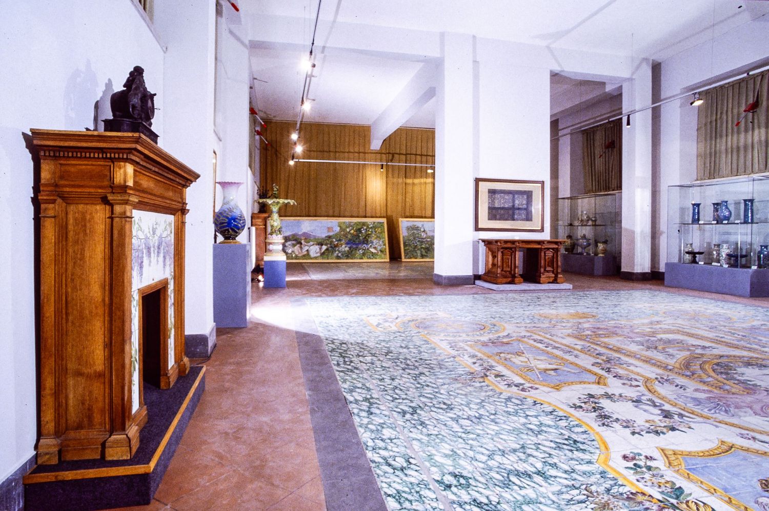 MAI Museo artistico industriale Interior view of an ornate museum gallery with patterned tiles and wooden display cases and fireplace.