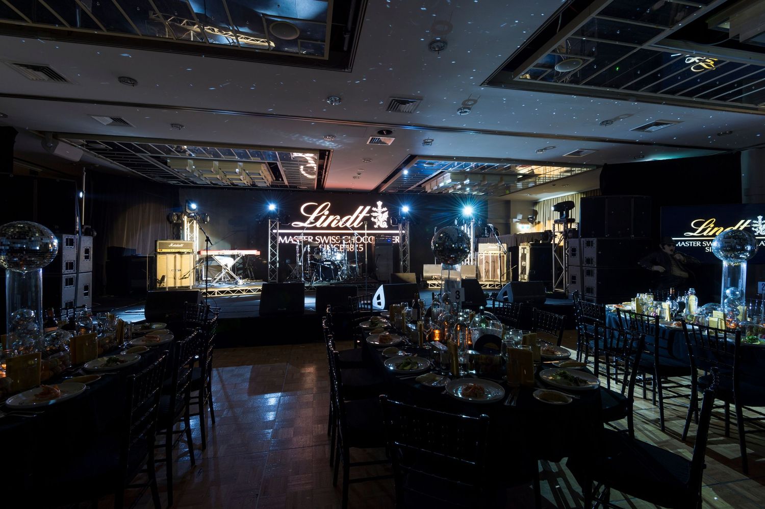 A dark nightclub interior with neon lights and multiple TV screens mounted on walls showing different content.