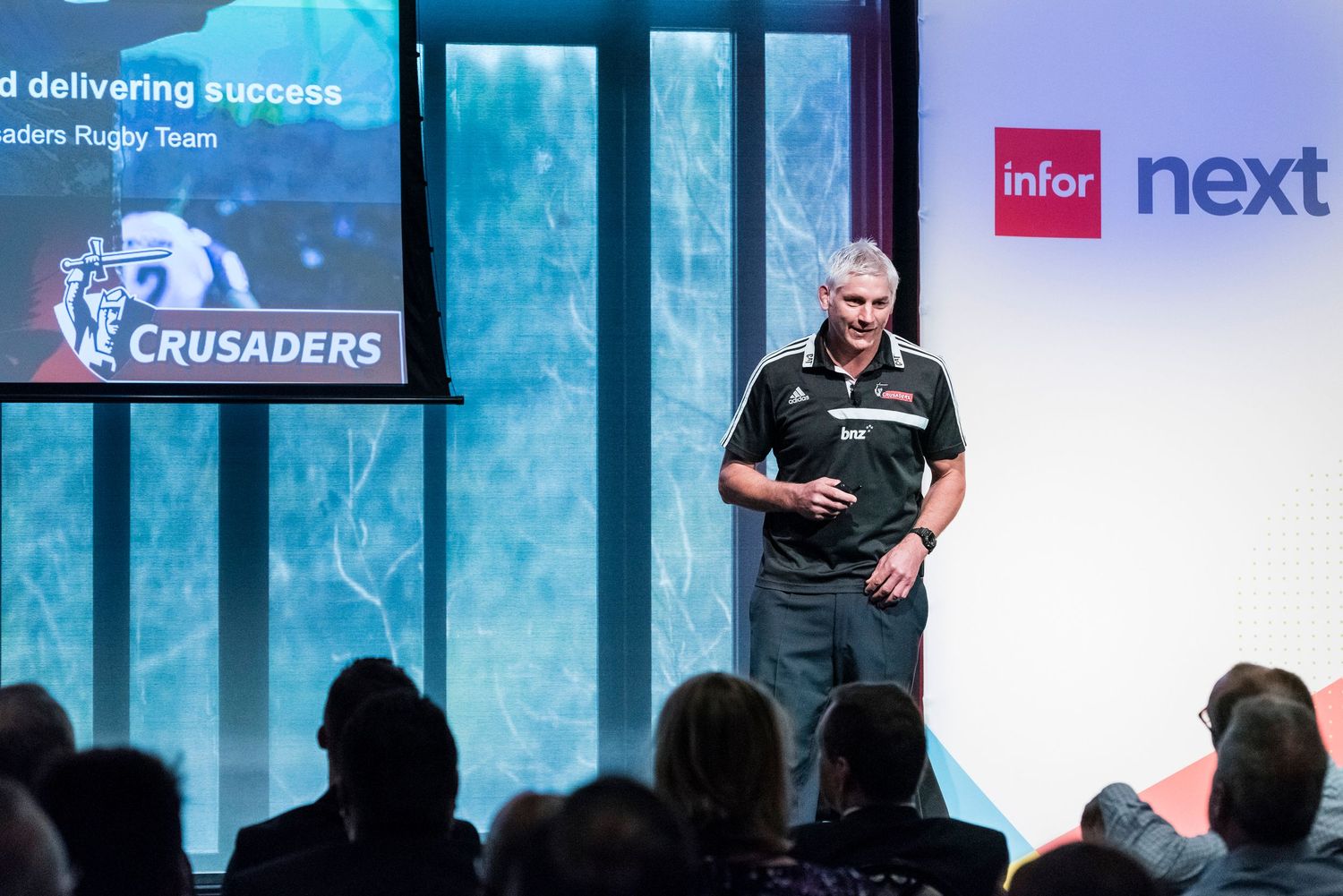 Conference stage with multiple screens displaying sports and business content.