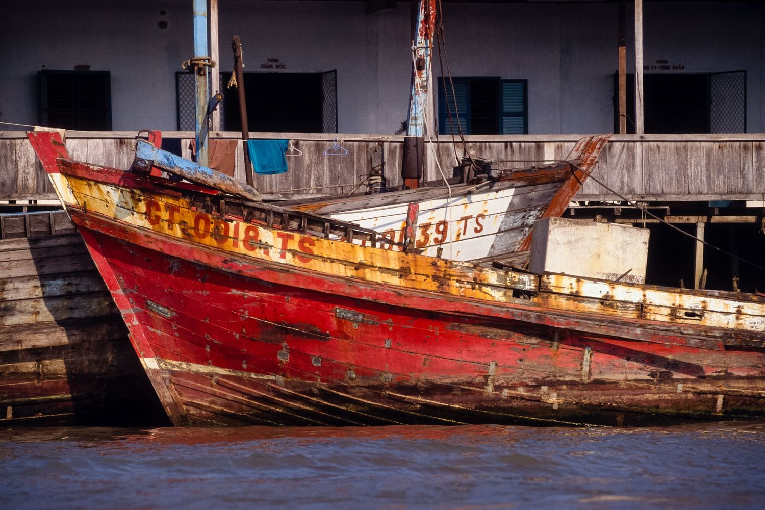 Row of weathered fishing boats in red and brown tones docked at the harbor.
