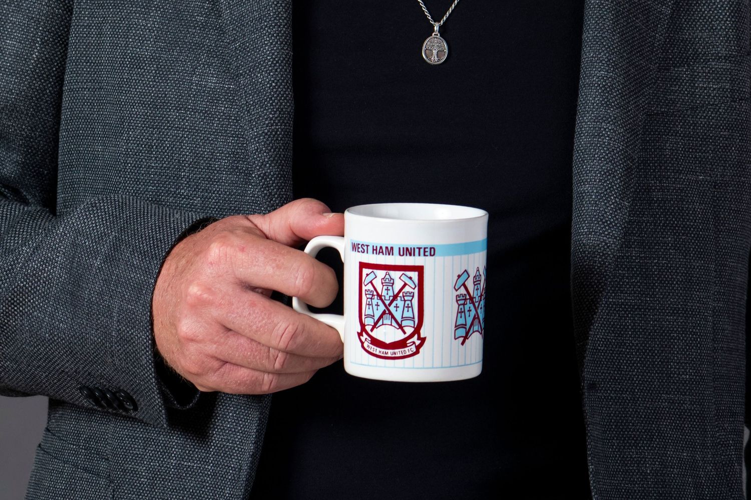 Coffee mug featuring a coat of arms design held against dark background.