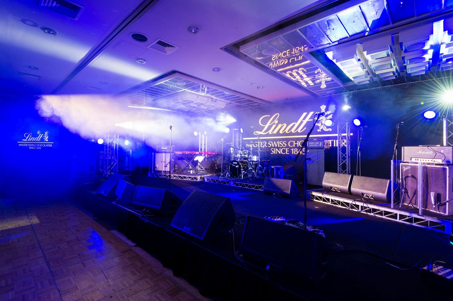 A series of blue-lit concert venue or nightclub interior shots showing stage lighting and atmospheric effects.