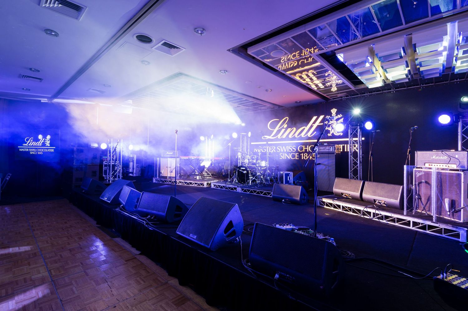 A nightclub interior with blue lighting and LED screens showcasing multiple views of the dance floor and stage setup.