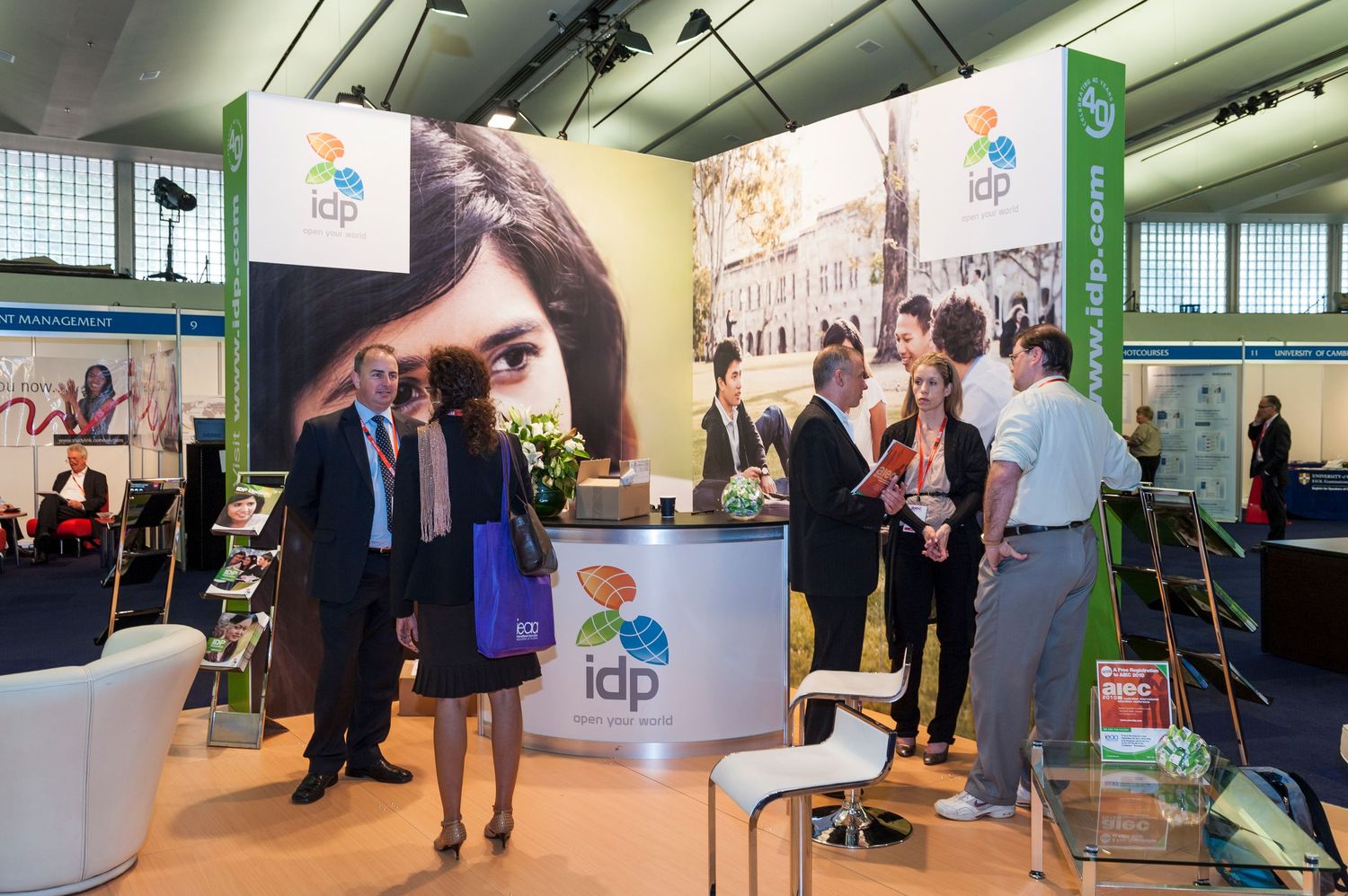 Trade show floor with exhibition booths and attendees walking through displays.