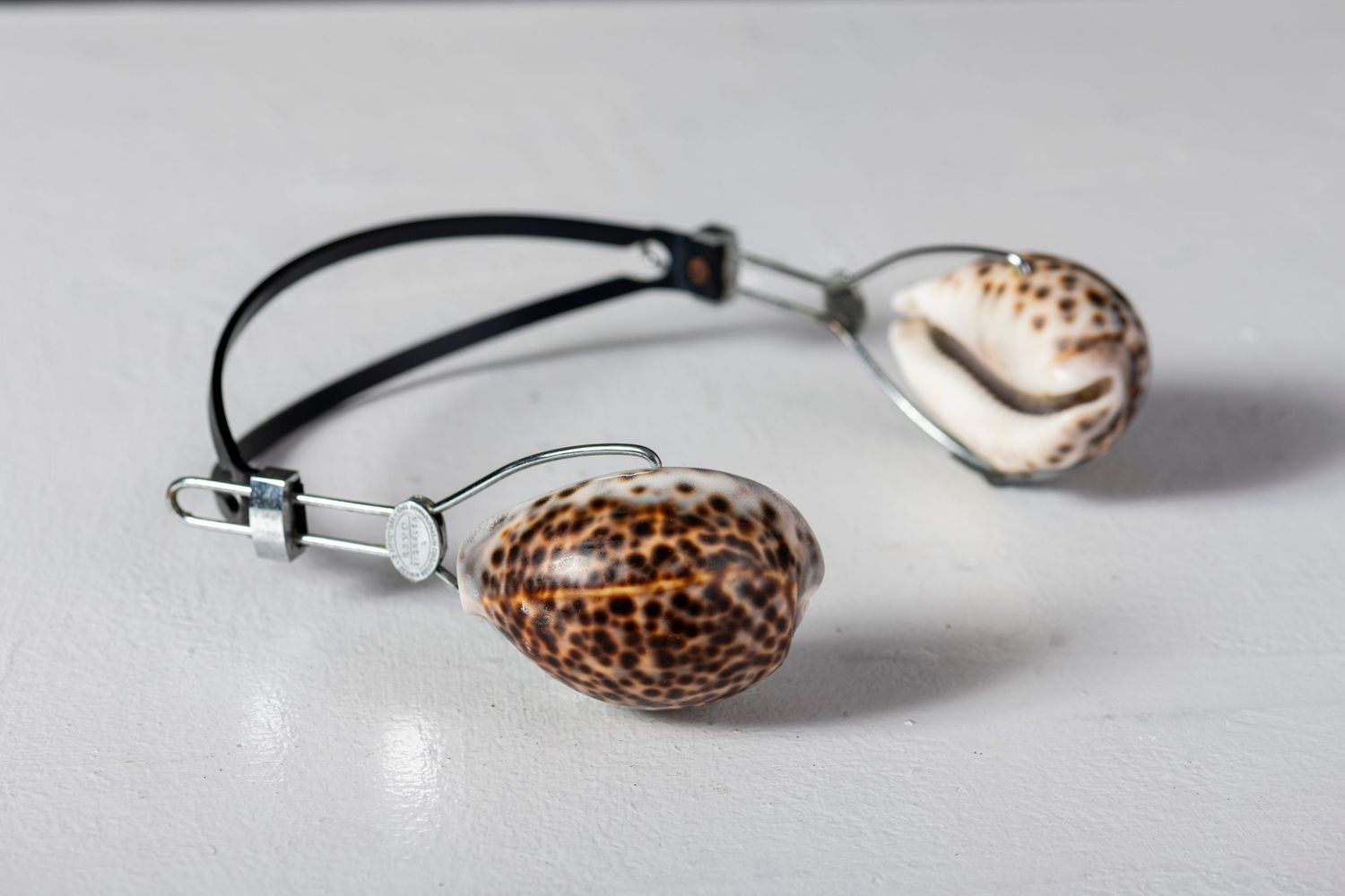 Close-up of decorative shell pendant on black cord against white background.