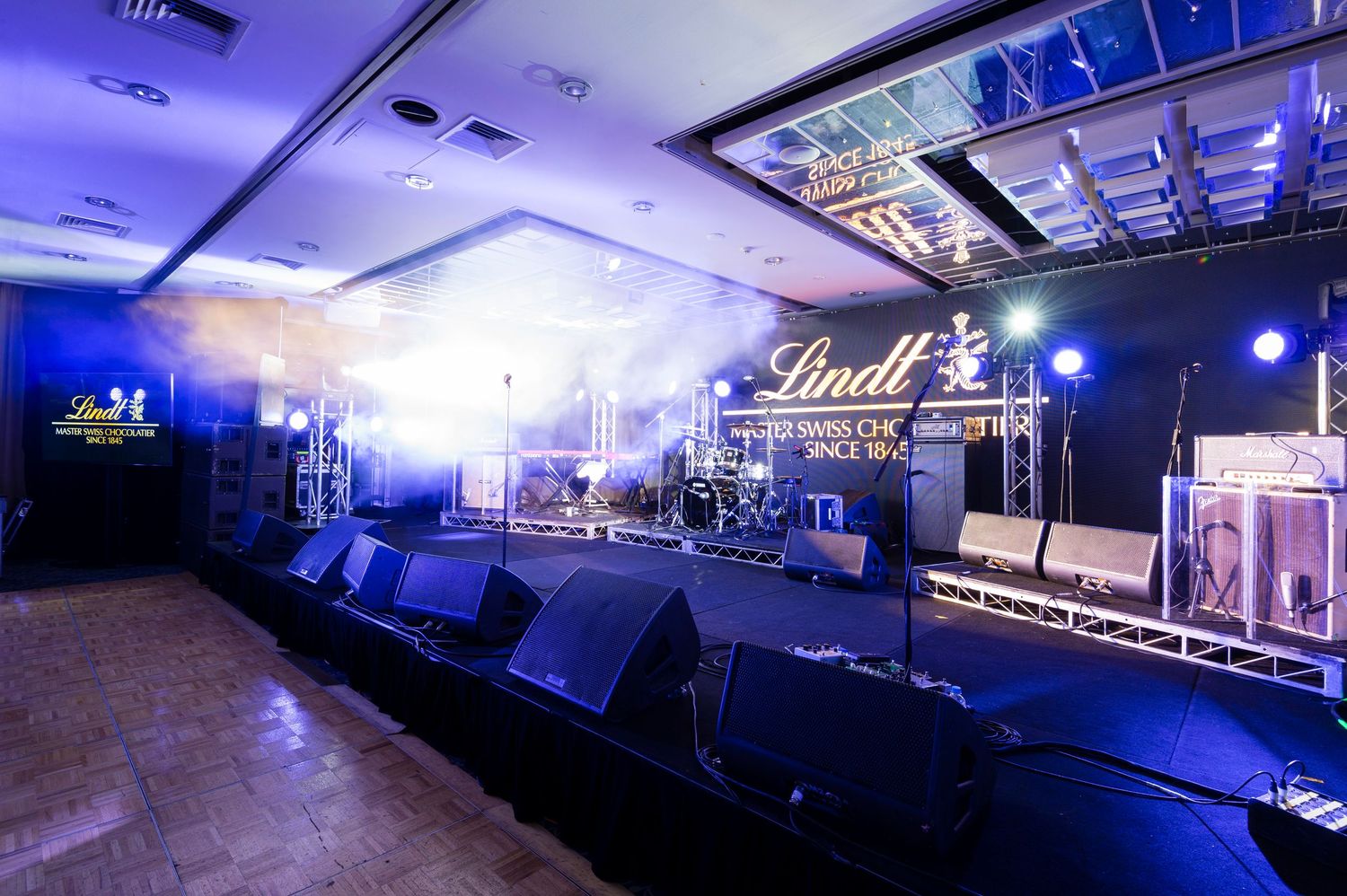 Modern nightclub interior with blue LED lighting and multiple screens mounted on dark walls creating an atmospheric ambiance.