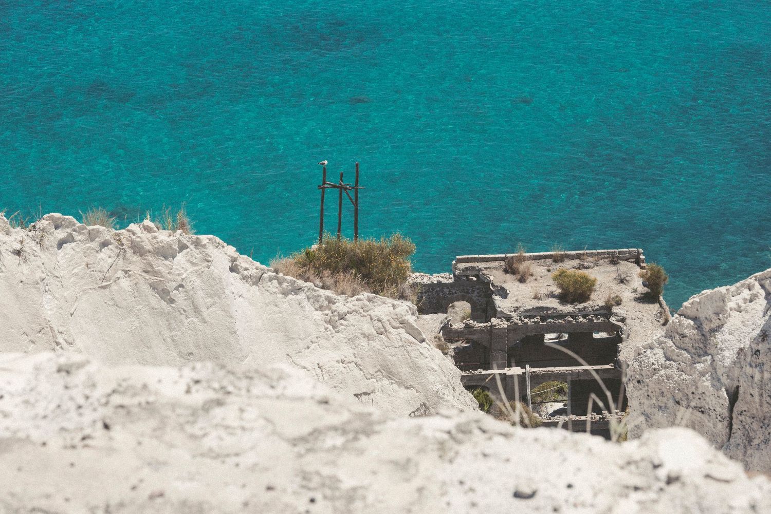 Aerial view of turquoise Mediterranean waters and white limestone cliffs along a rugged coastal shoreline.