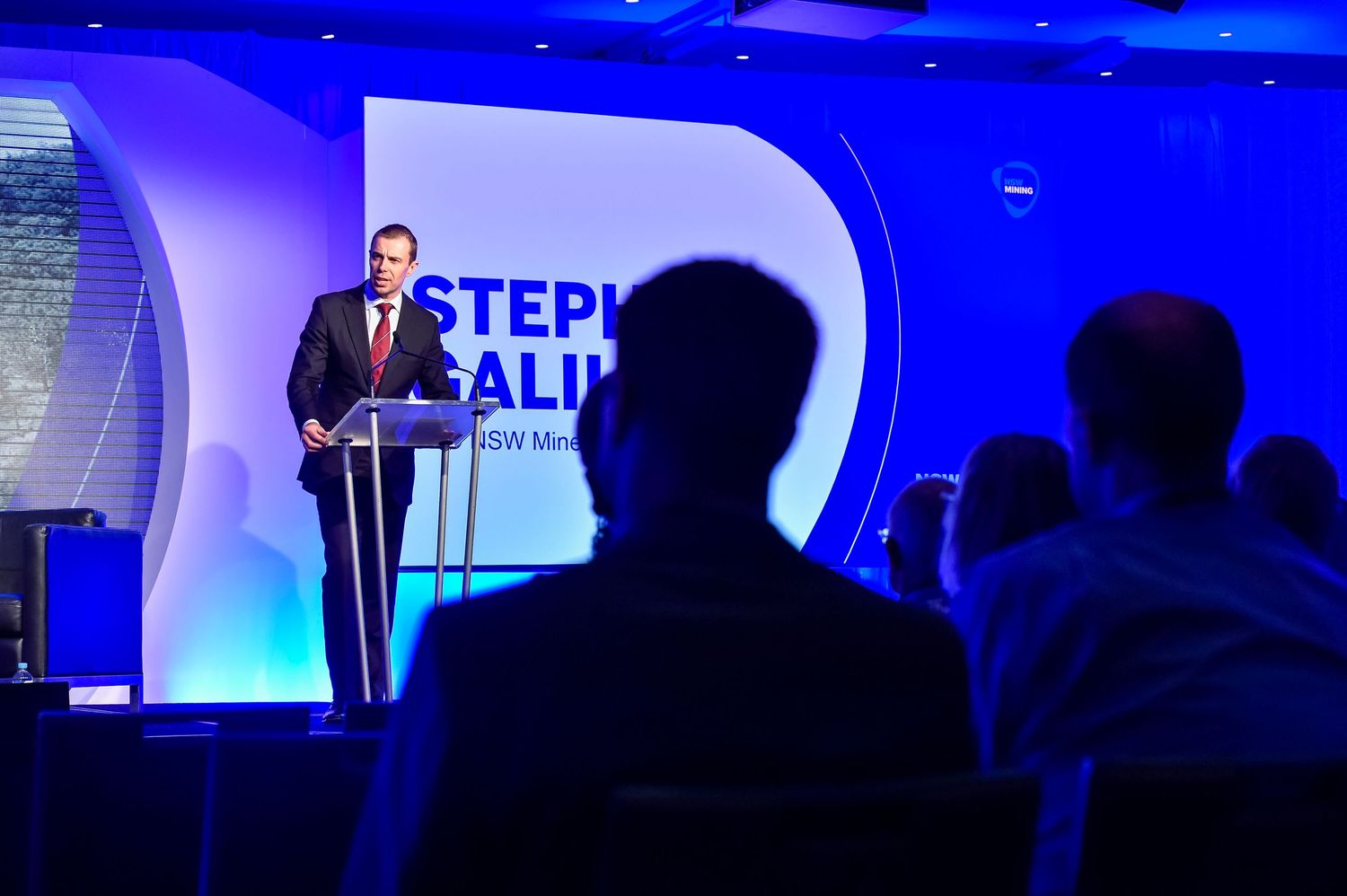 Professional stage setup with blue lighting and digital displays for a corporate presentation.