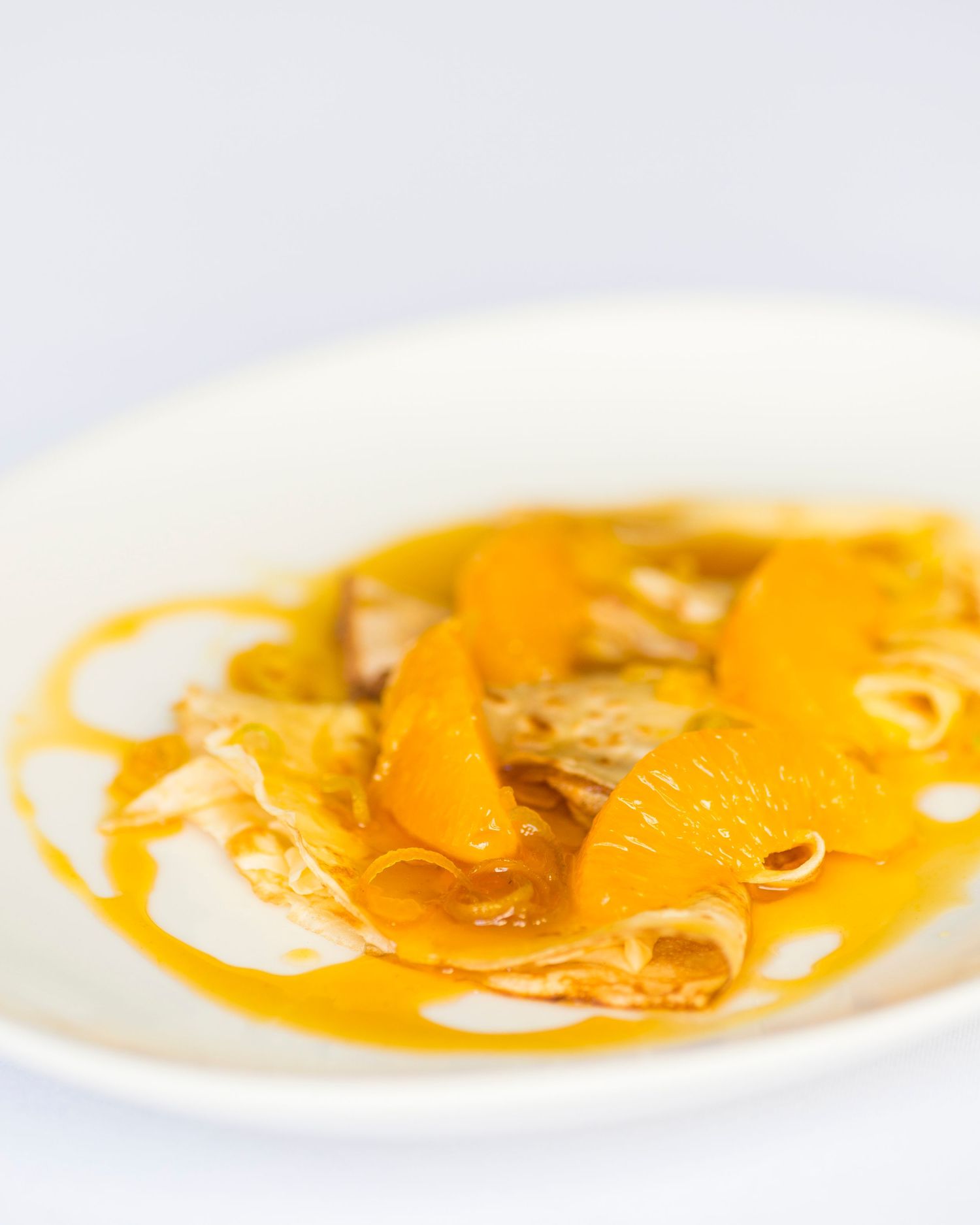 Sliced oranges in syrup served on a white plate with delicate presentation.