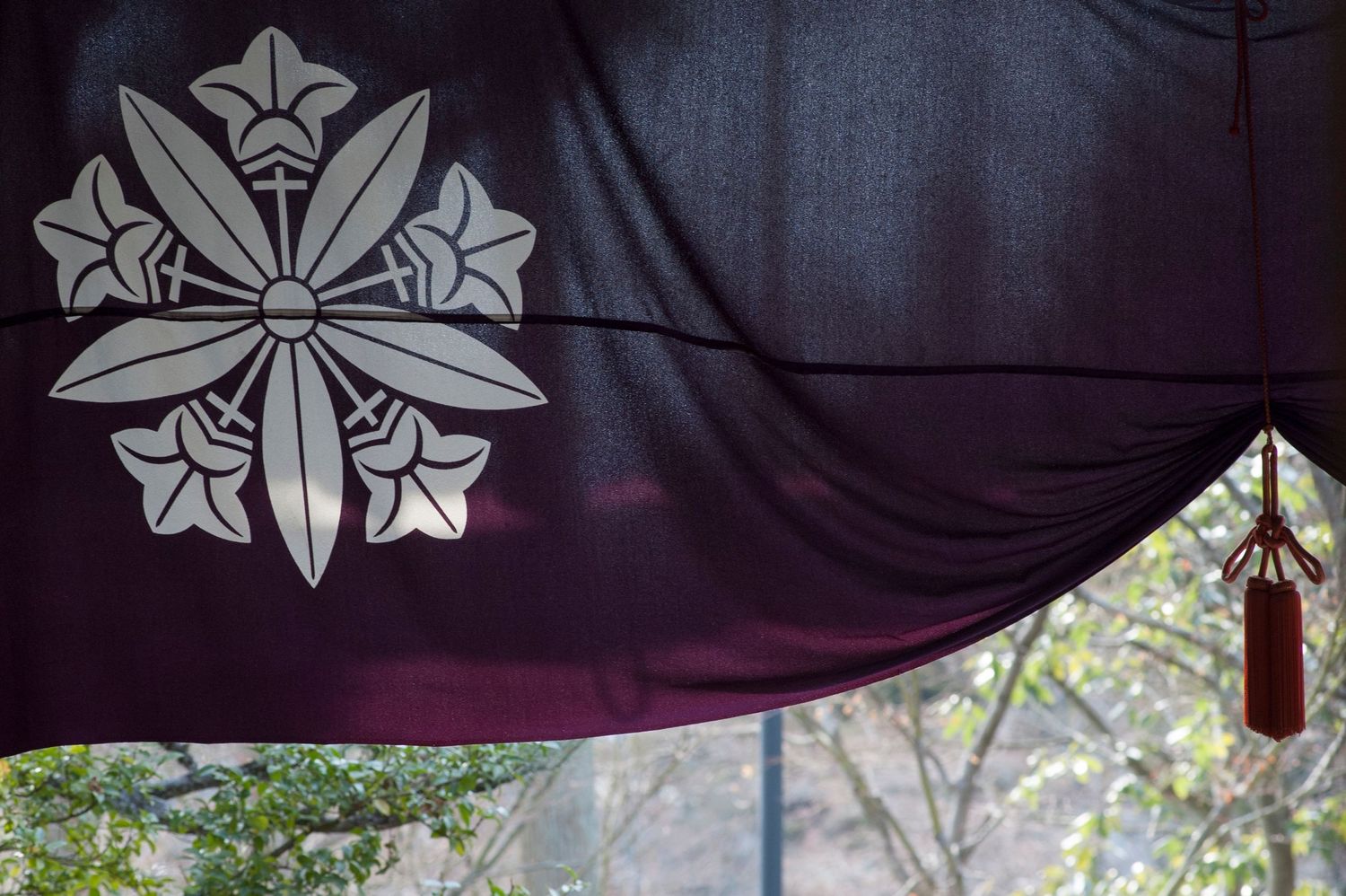 Decorative fabric banner with embroidered floral crest designs against dark background.