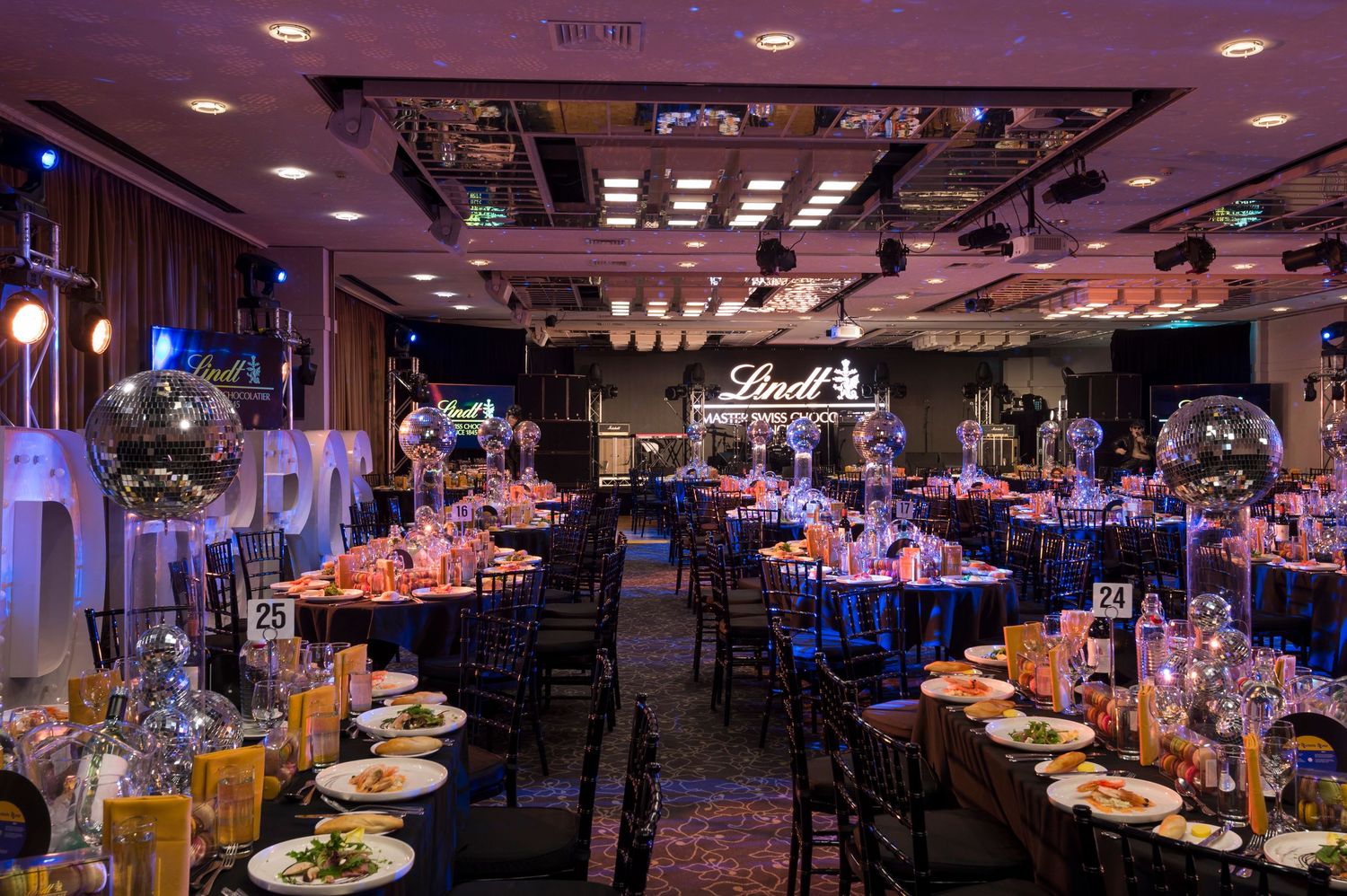 Large banquet hall with blue uplighting and elegant table settings for a formal event.