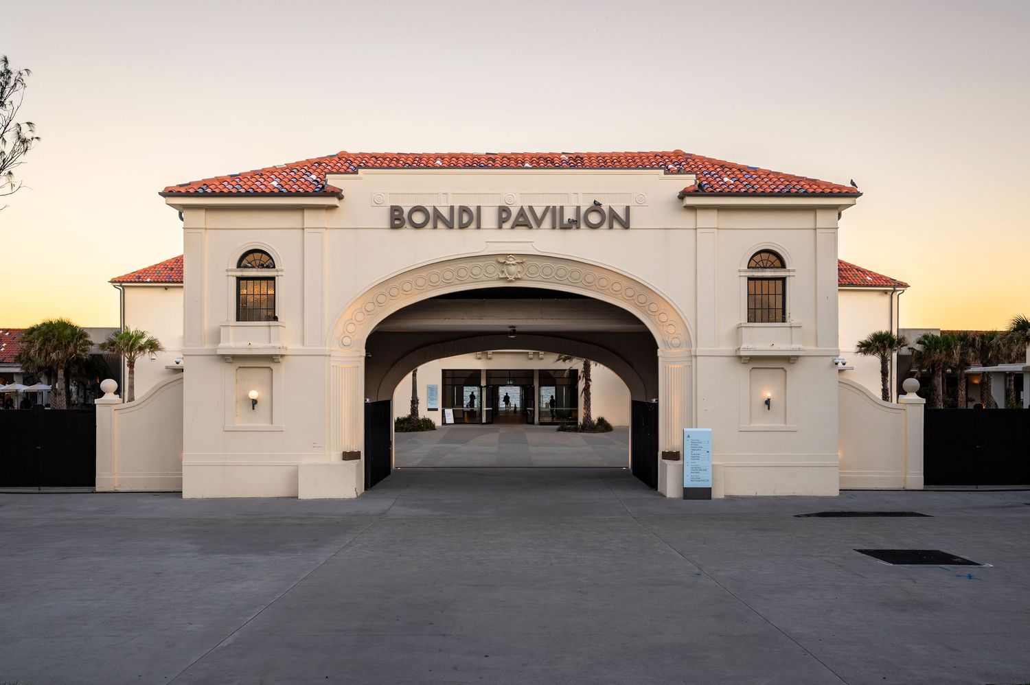 The historic Bondi Pavilion building facade at sunset with its white arches and Mediterranean architectural style.
