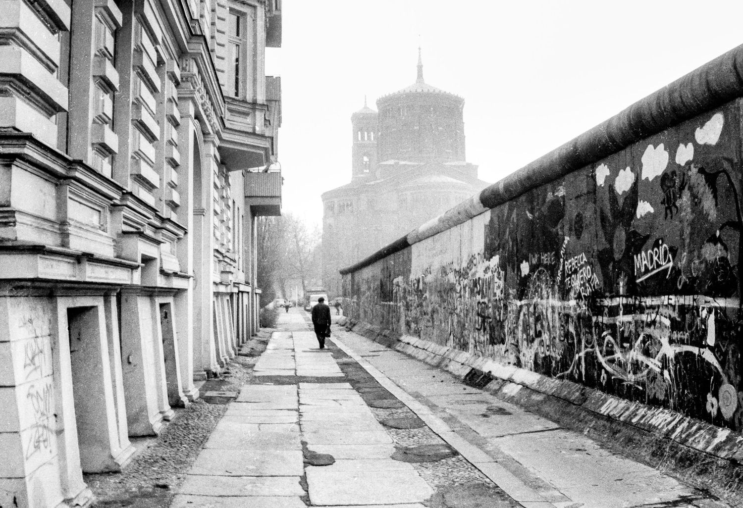 Various views of the Berlin Wall stretching through urban areas with buildings visible.