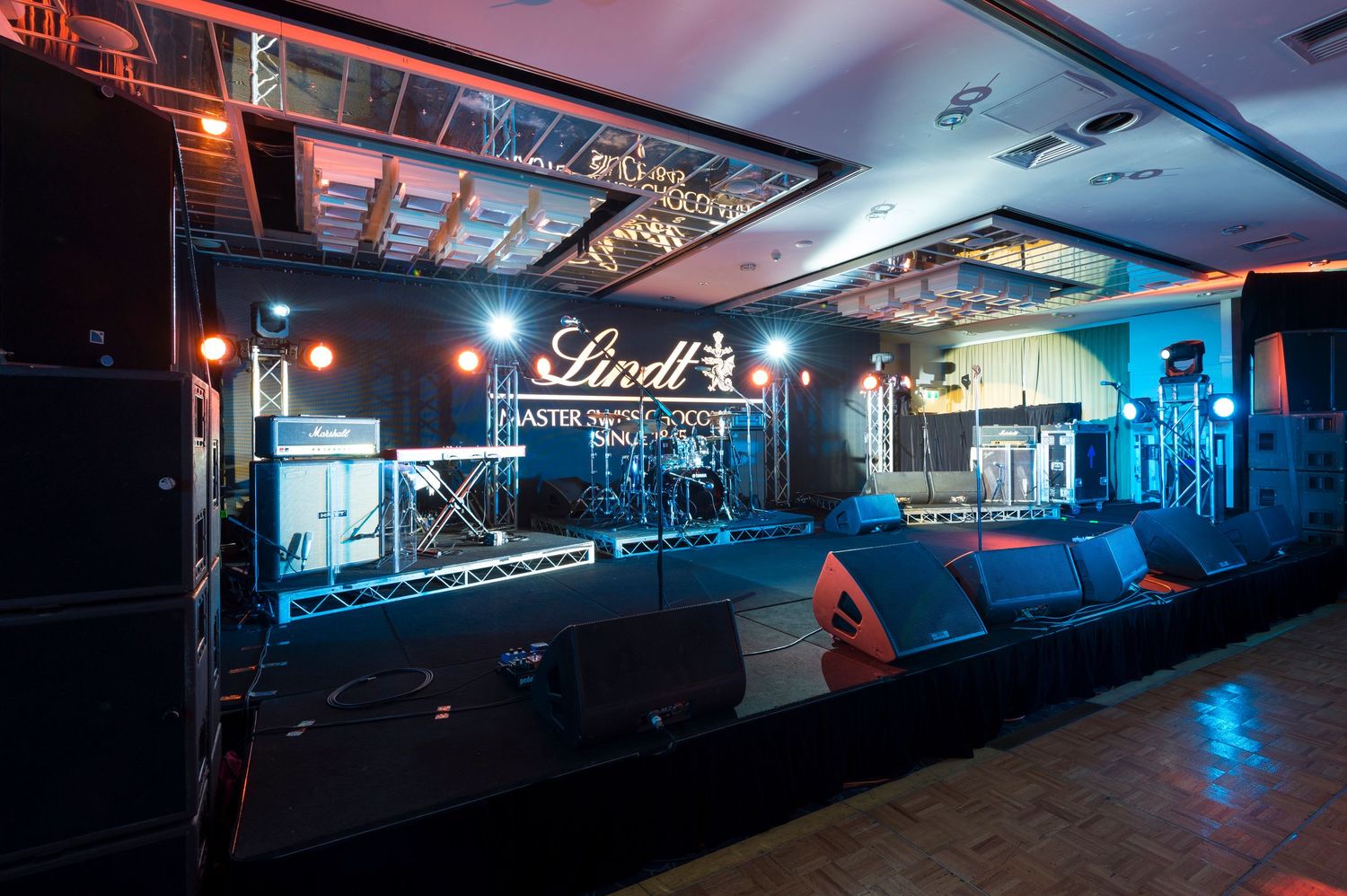 Panoramic view of a dimly lit bar interior with neon blue lighting and modern industrial design elements.