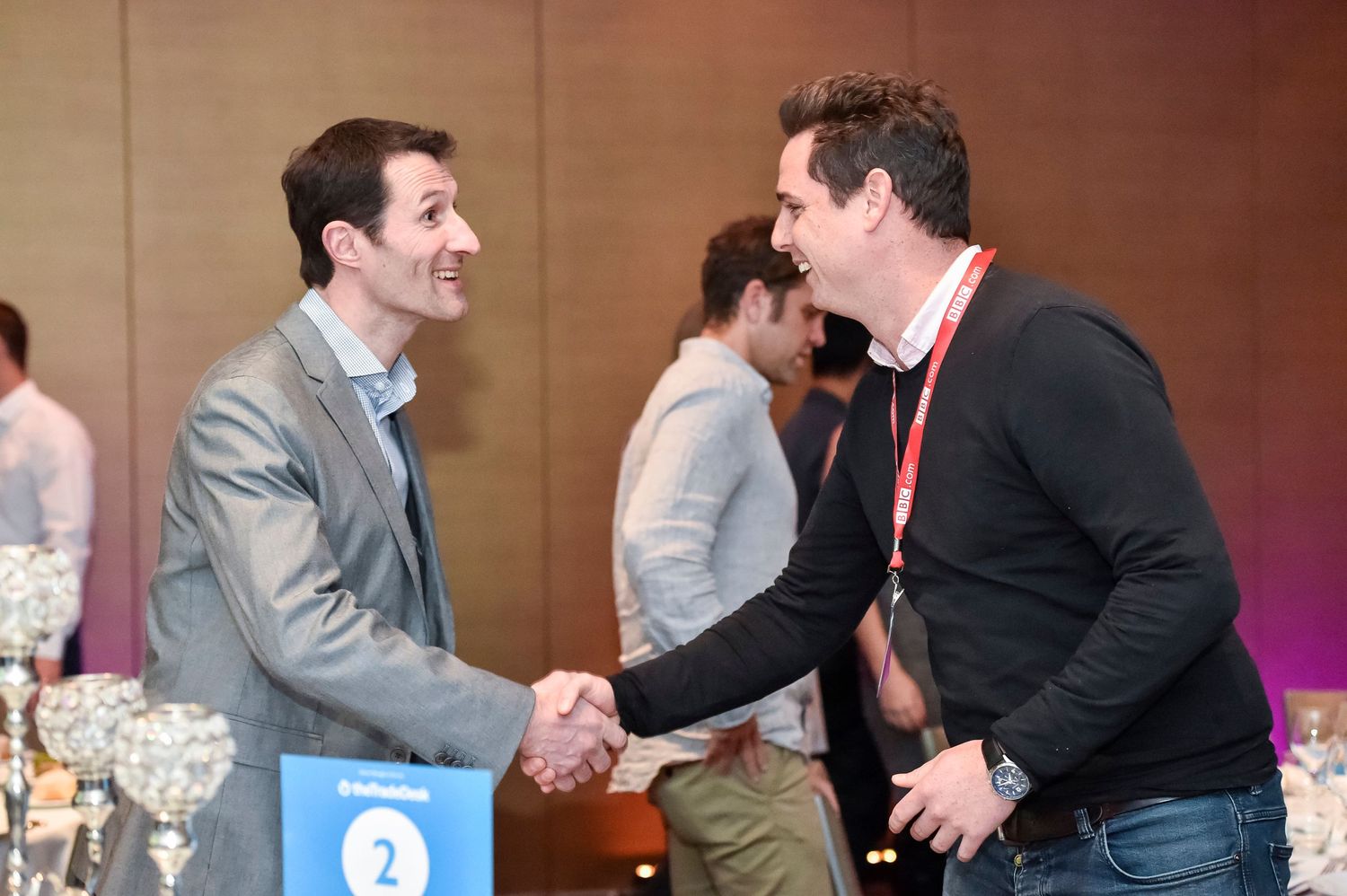 Business professionals shake hands and network at a corporate conference event.