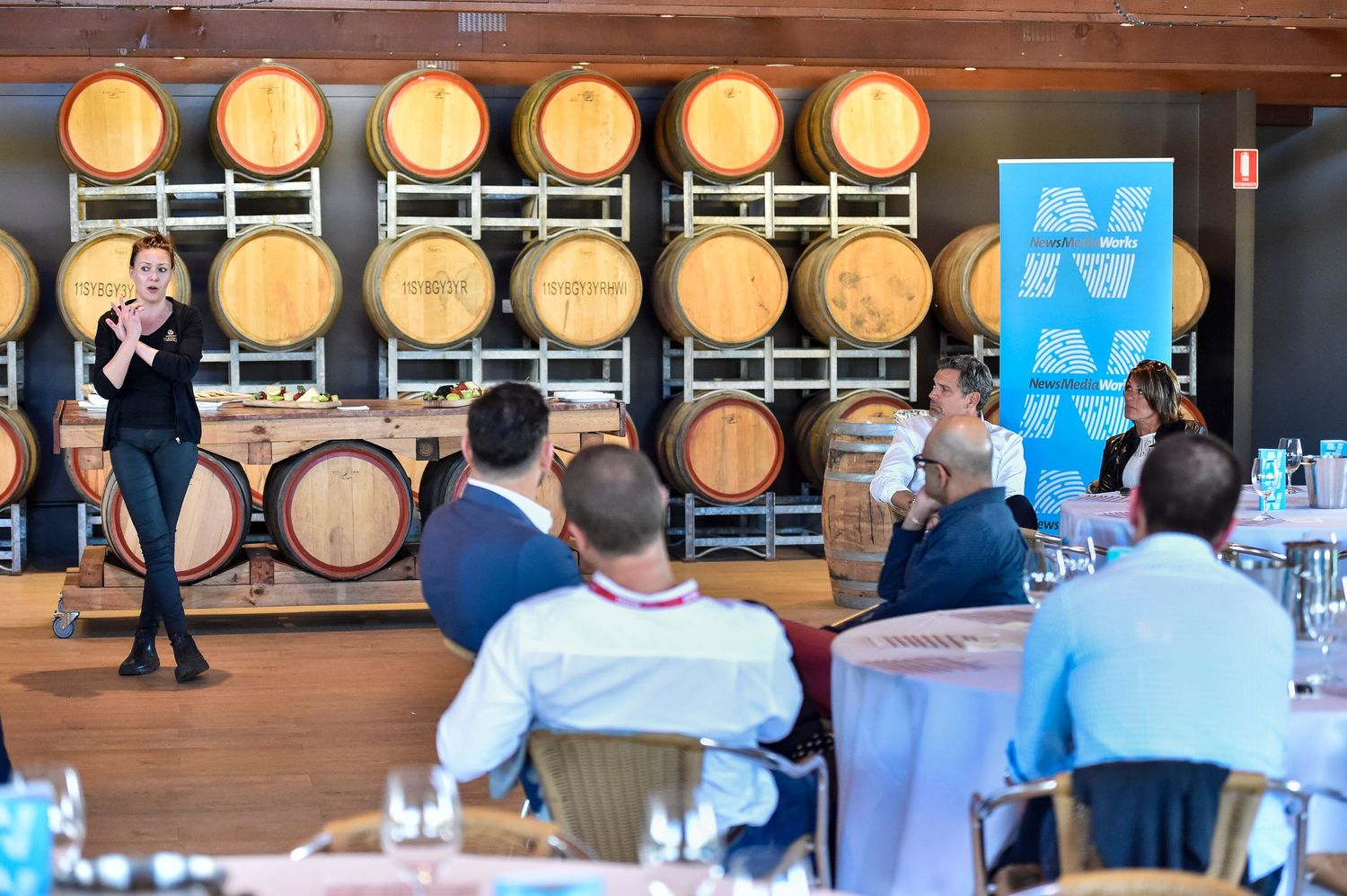 Wine barrels line the wall of a rustic tasting room during a business event at a winery in the Hunter Valley
