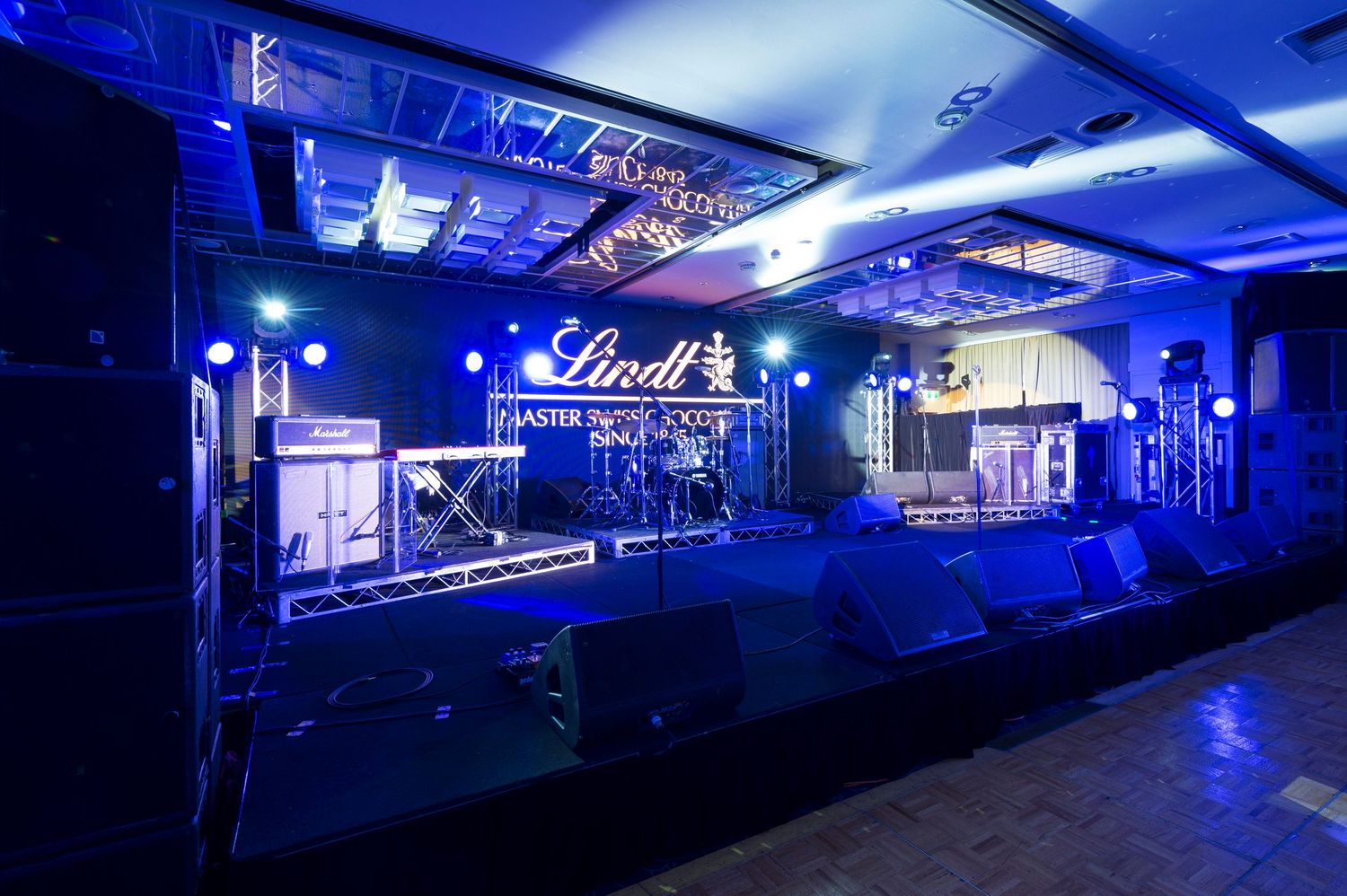 A panoramic view of a dimly lit nightclub interior illuminated by blue lighting and neon signs.