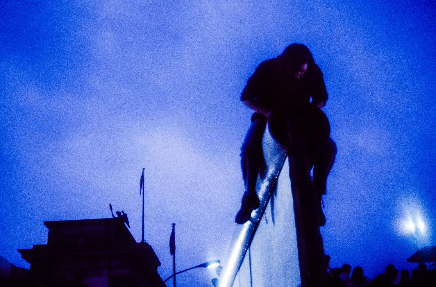 Silhouettes of people against a dark blue sky with spotlights creating an atmospheric nighttime scene.