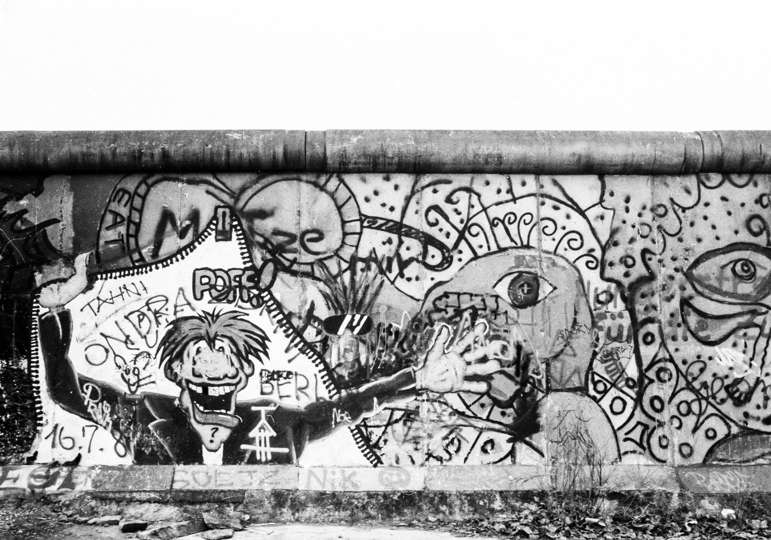 Graffiti art covering a section of the Berlin Wall featuring cartoon-style drawings.