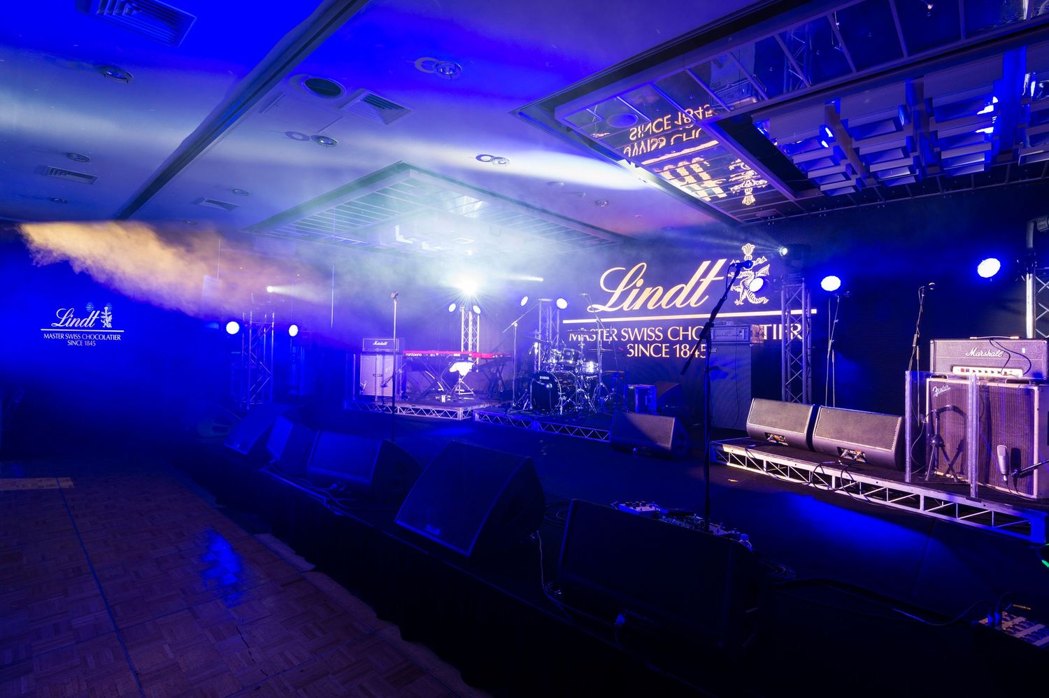 A nightclub interior with blue lighting and stage equipment setup for live performances.