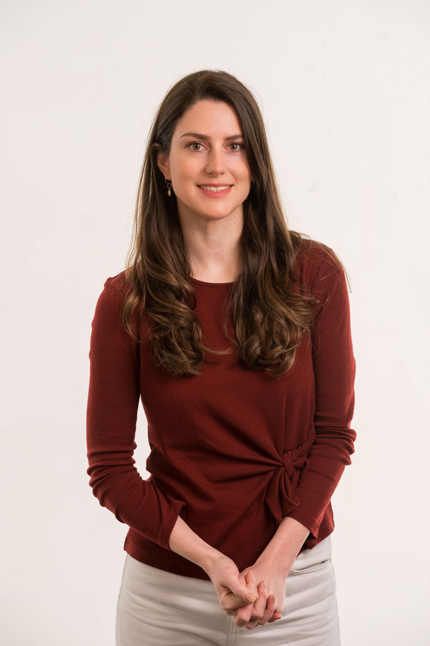 Professional portraits showing person in burgundy sweater and light colored skirt.