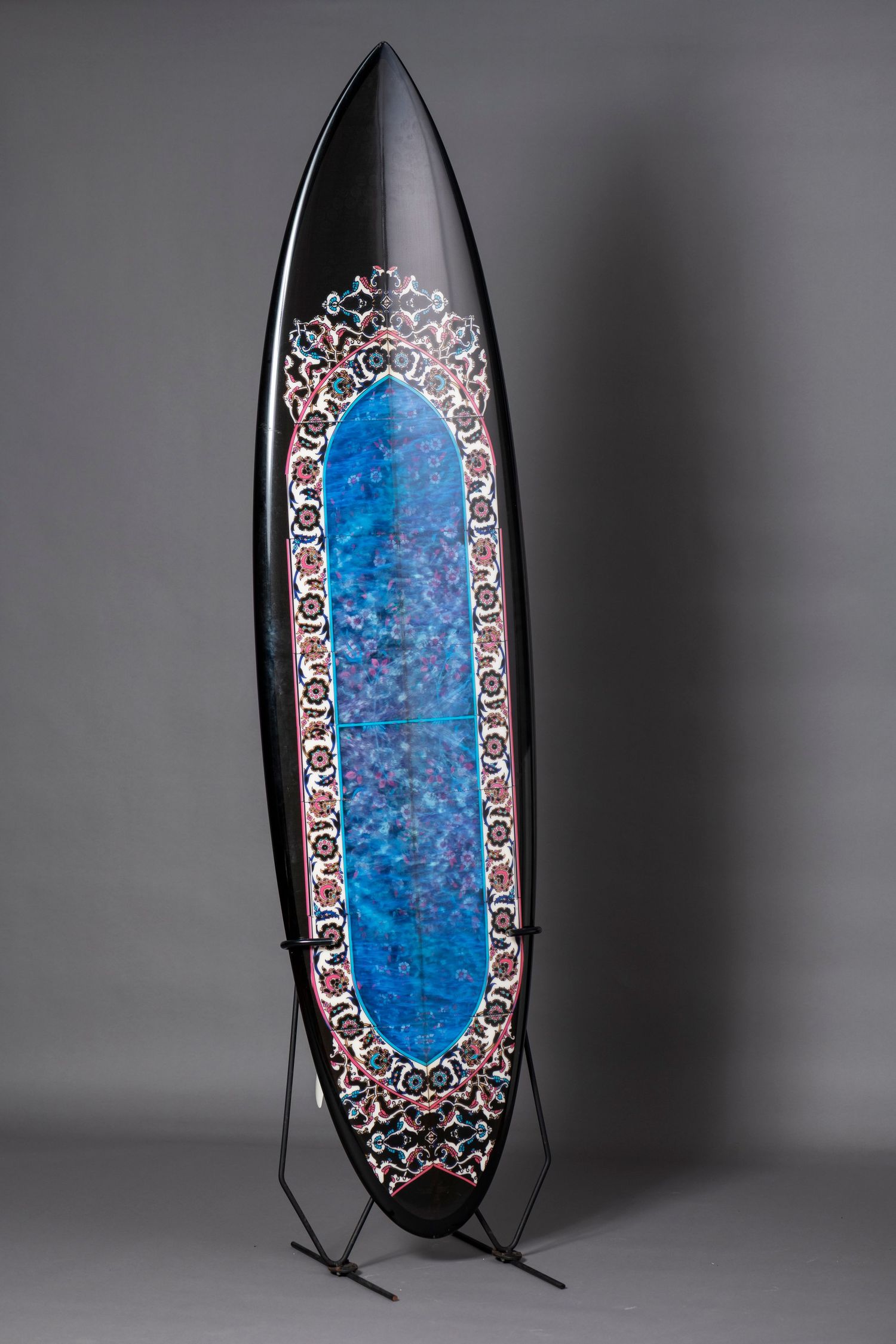 Decorative blue glass panel with ornate metallic border design displayed in a vertical standing frame.