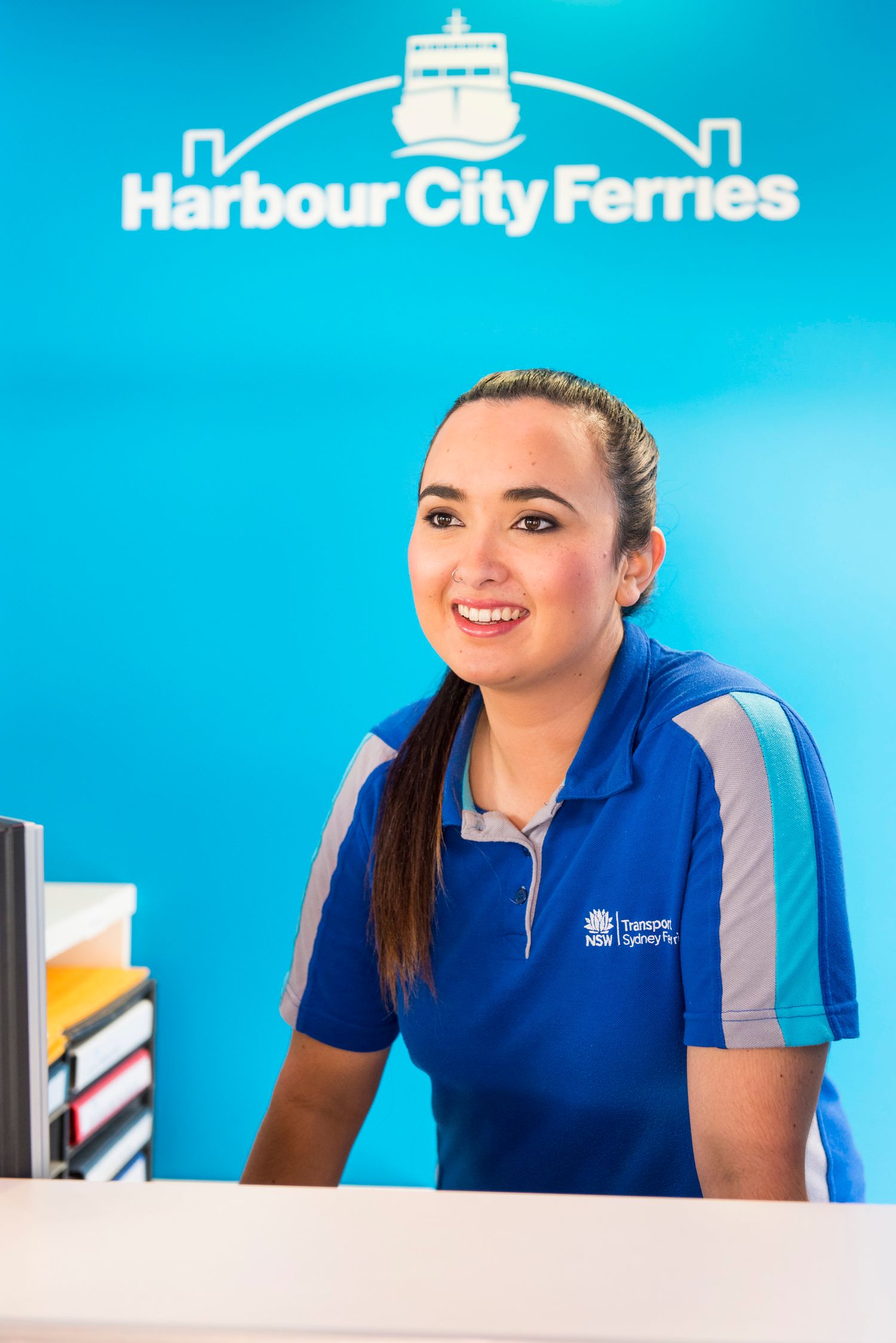 Harbour City Ferries employee uniforms shown against bright blue branded background.