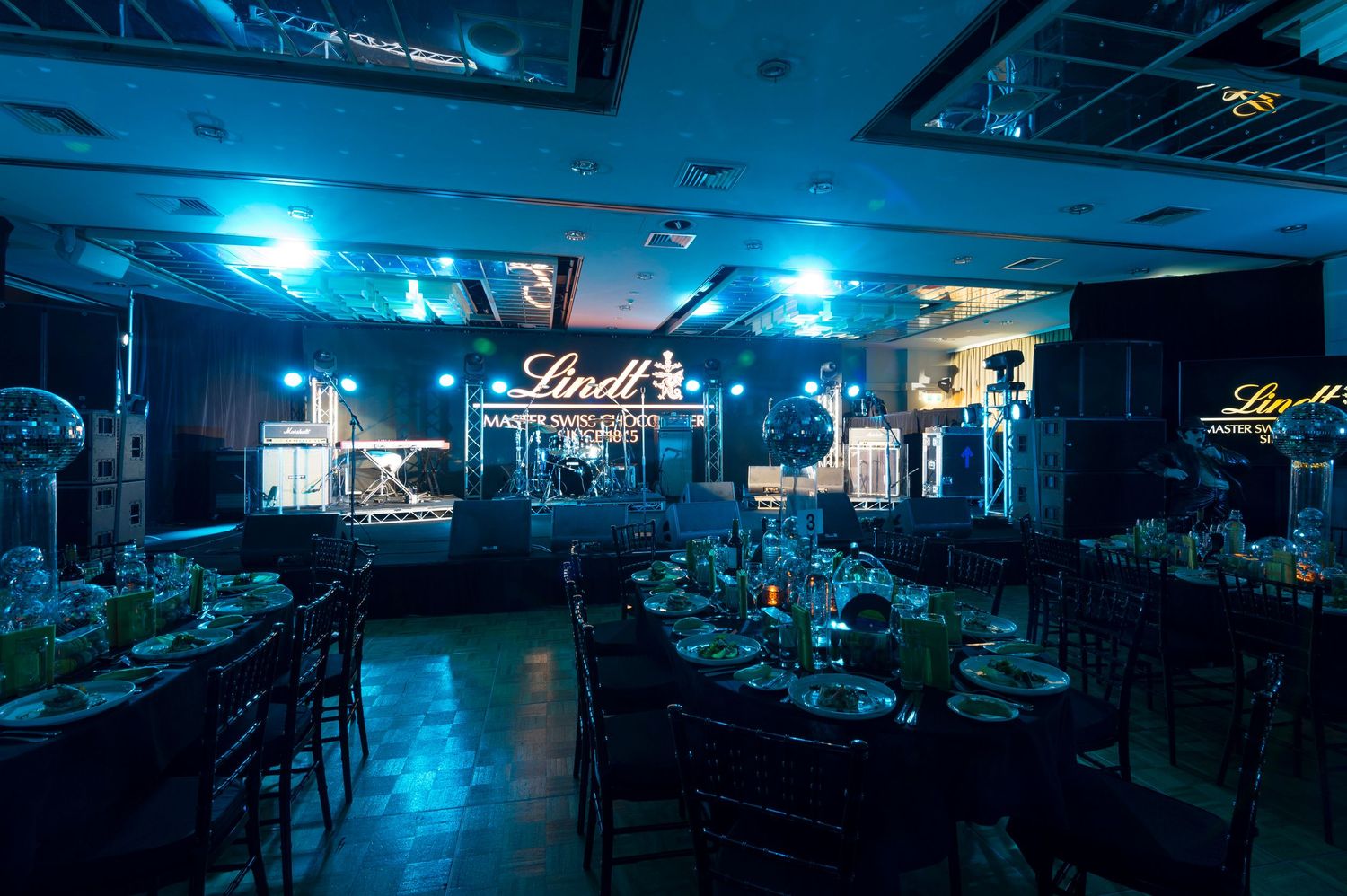 A series of dimly lit arcade rooms bathed in blue neon lighting creates a moody gaming atmosphere.