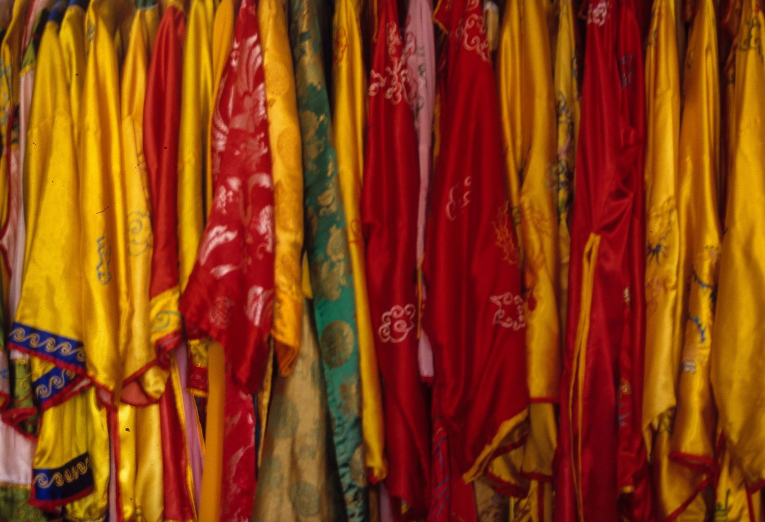 Colorful display of hanging red, yellow and green traditional garments or fabrics.