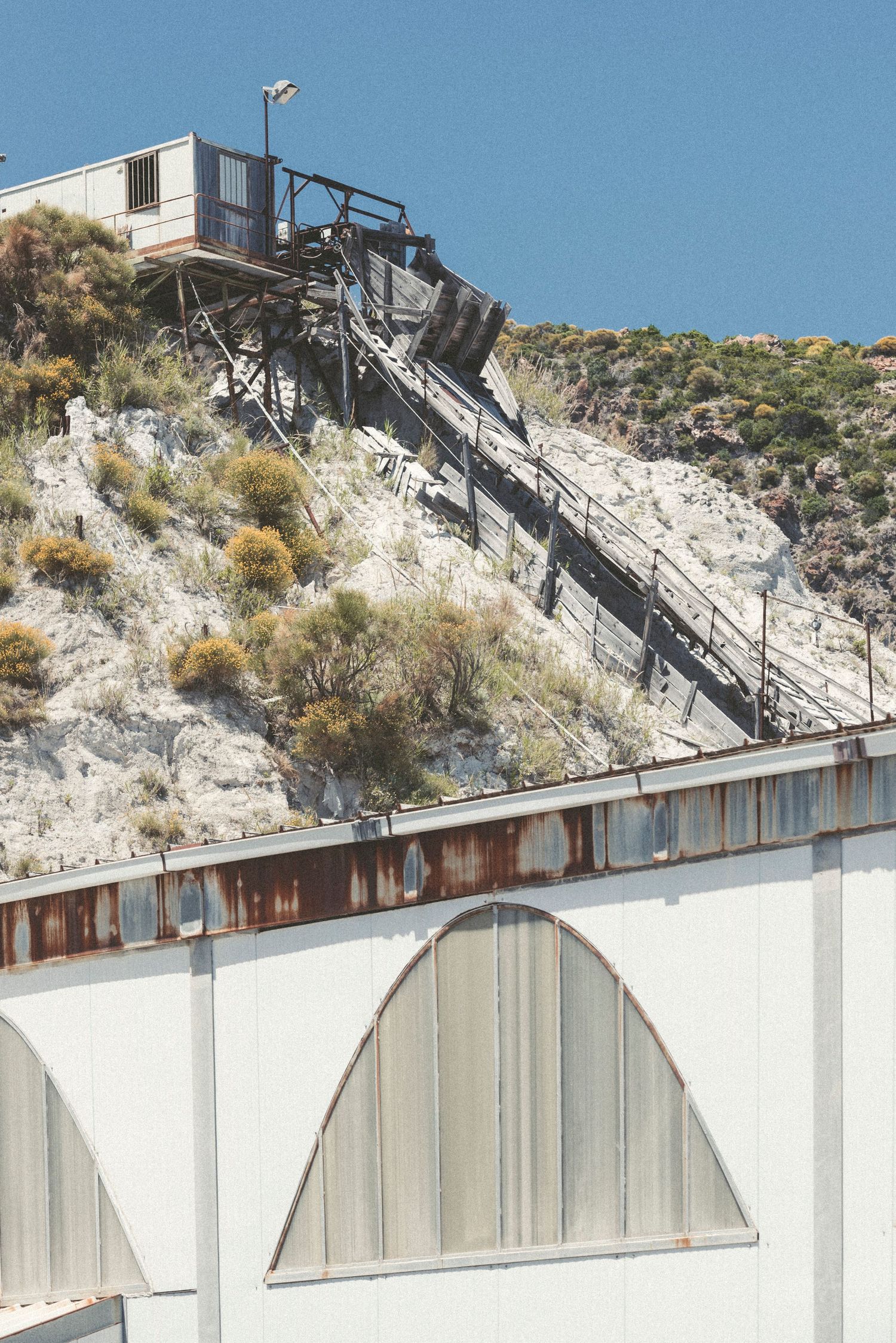 A steep staircase leads up a rocky hillside to a small structure, with white arched walls visible below.