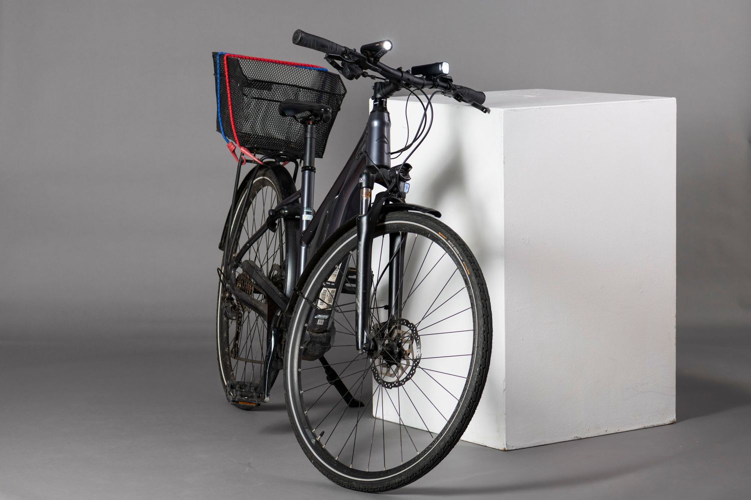 Parts of a black bicycle shown in segments on white display blocks against a gray backdrop.