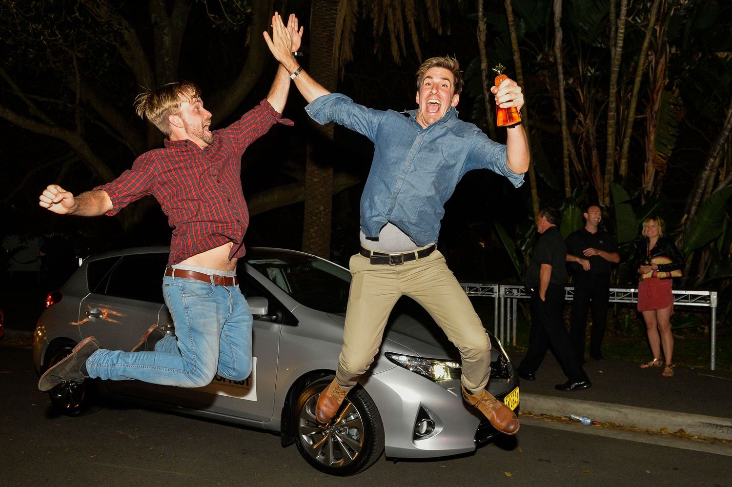 A sequence of photos showing two people falling while attempting a stunt or dance move in a nighttime setting.