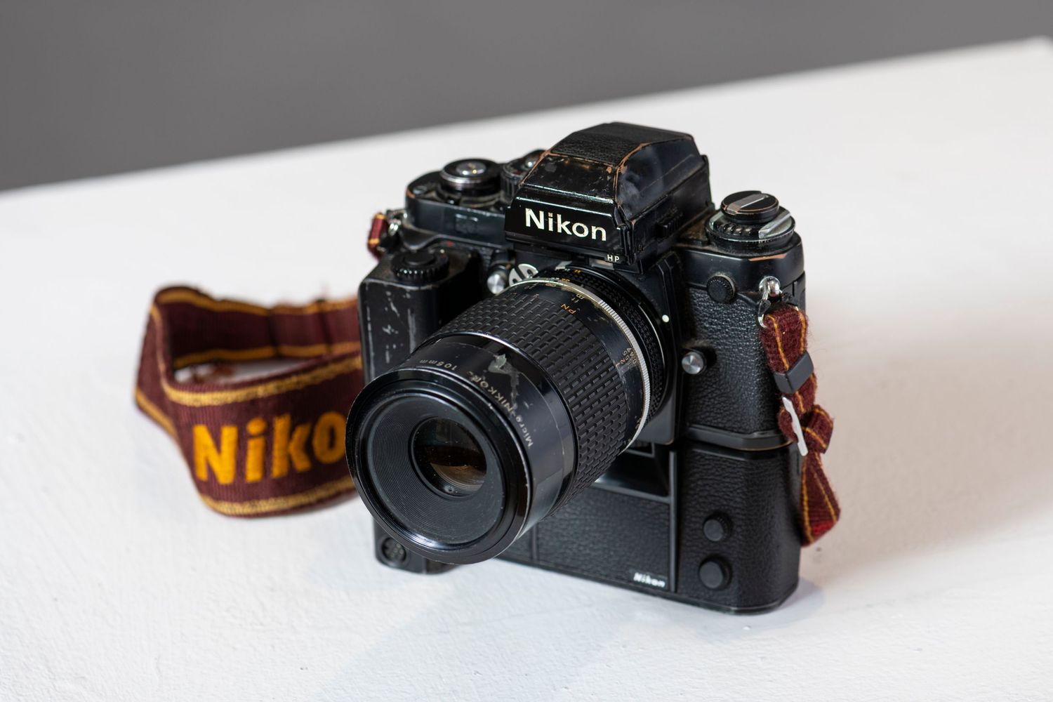 A sequence of four photos showing a Nikon camera at different angles on a white surface with leather strap details.